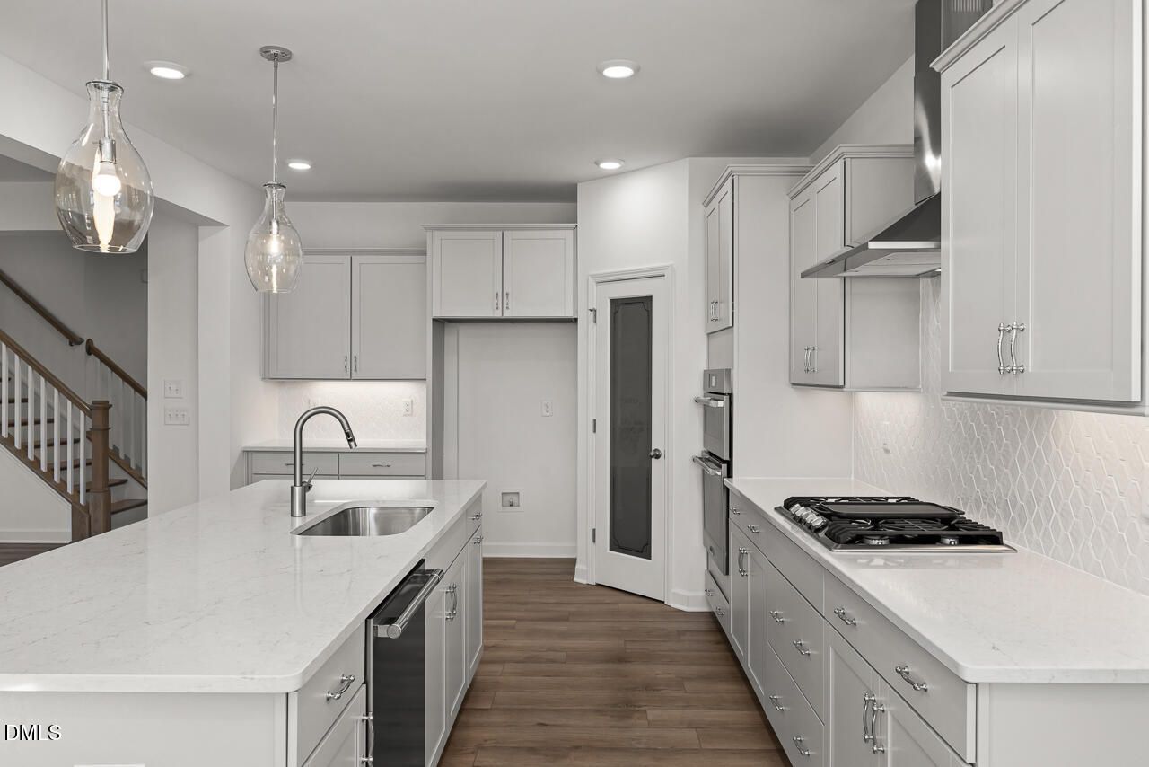 Bright white kitchen with quartz island, gas cooktop, stainless appliances in Davidson Homes The Cypress B II, Angier NC