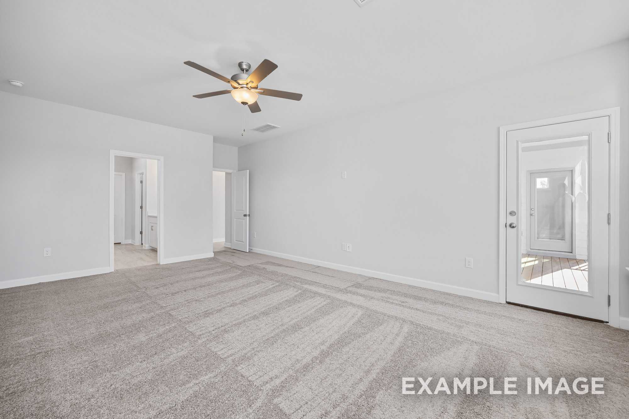 Spacious living room in The Cypress D II with gray carpet, ceiling fan, open doorways, and sliding glass patio door, Davidson Homes Angier NC