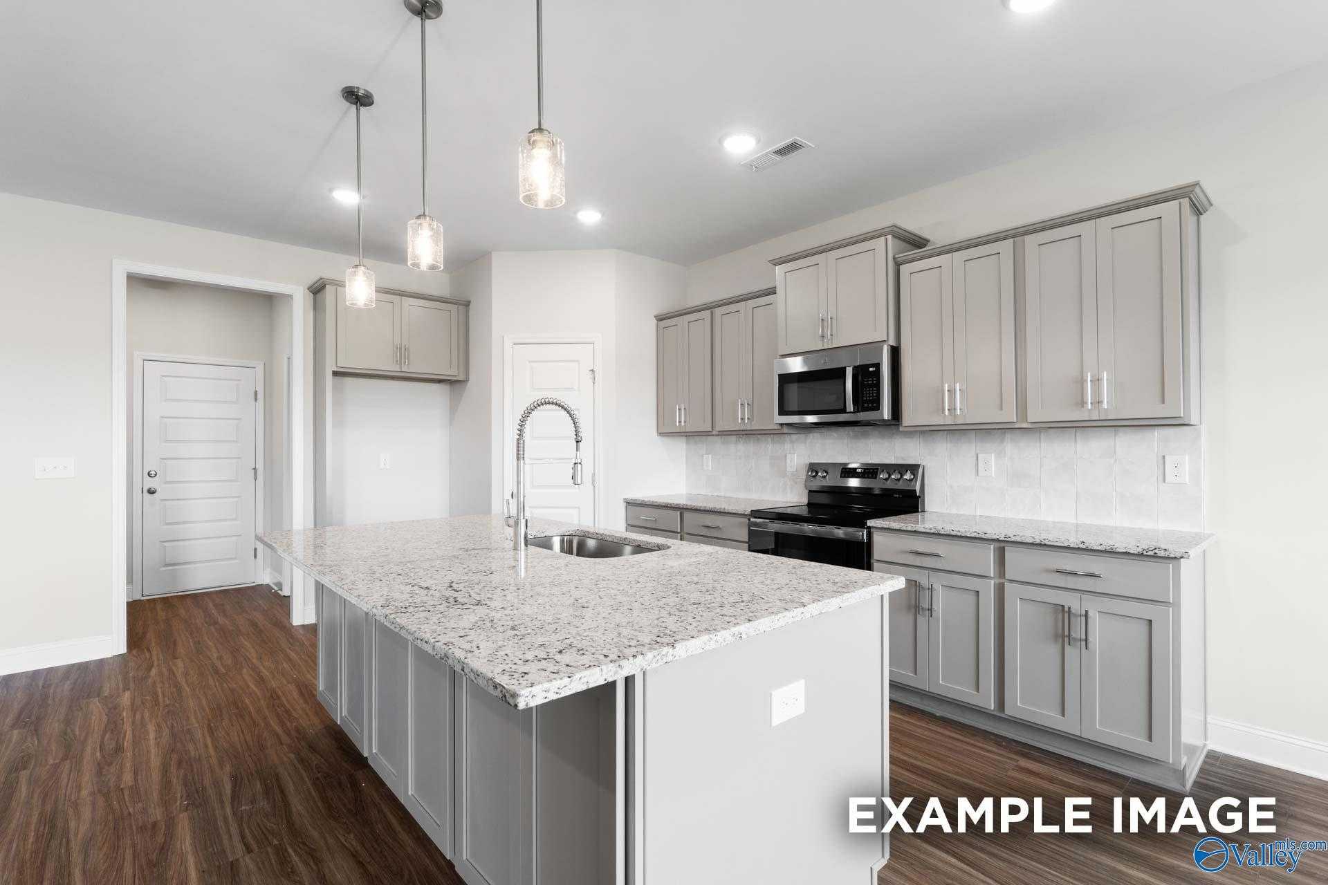Modern kitchen featuring gray shaker cabinets, granite island sink, stainless steel appliances in Davidson Homes The Montgomery, Hartselle, AL