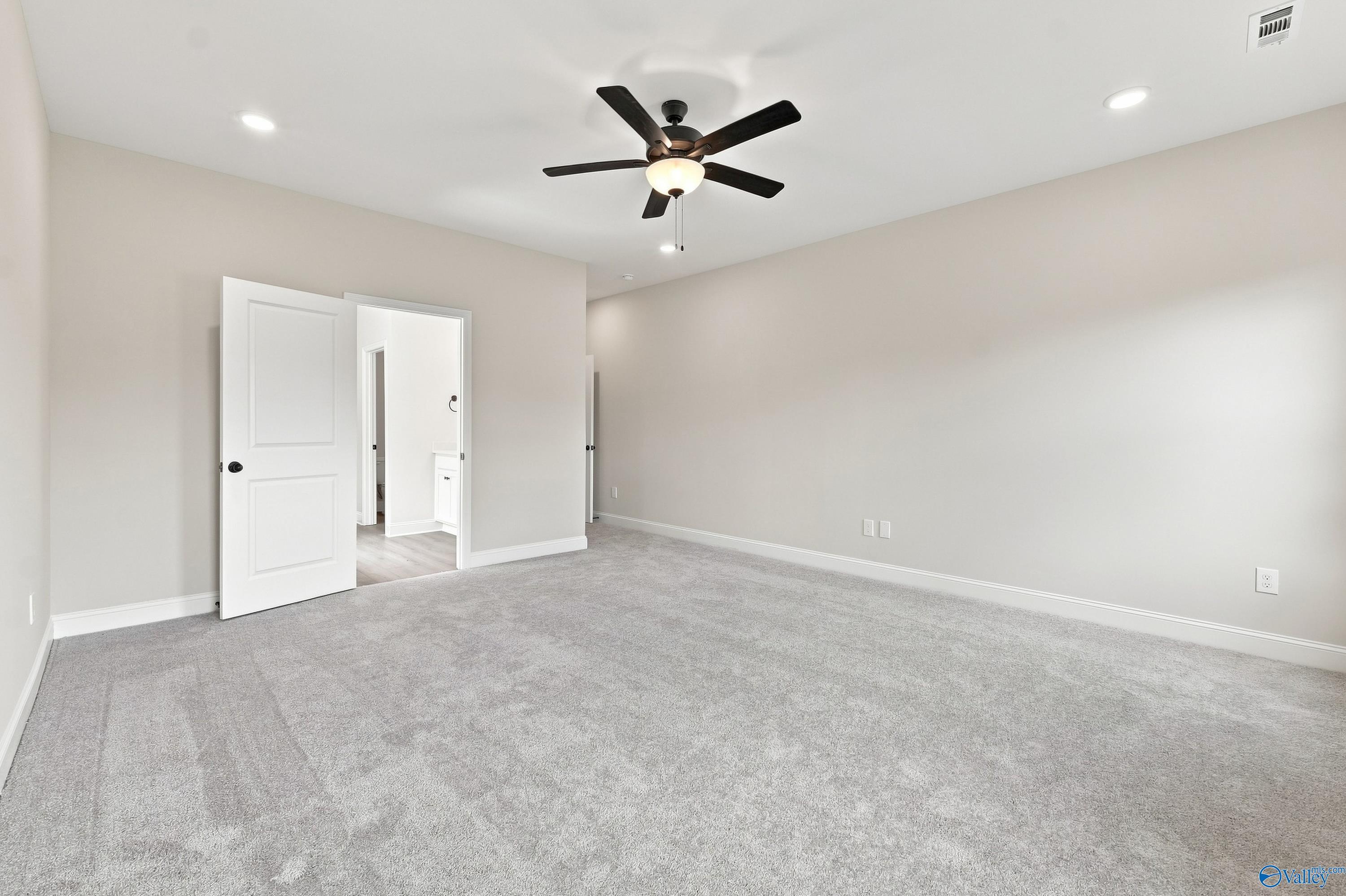 Spacious bedroom with grey carpet and ceiling fan in The Rockford B floor plan by Davidson Homes in Kendall Downs, Toney.