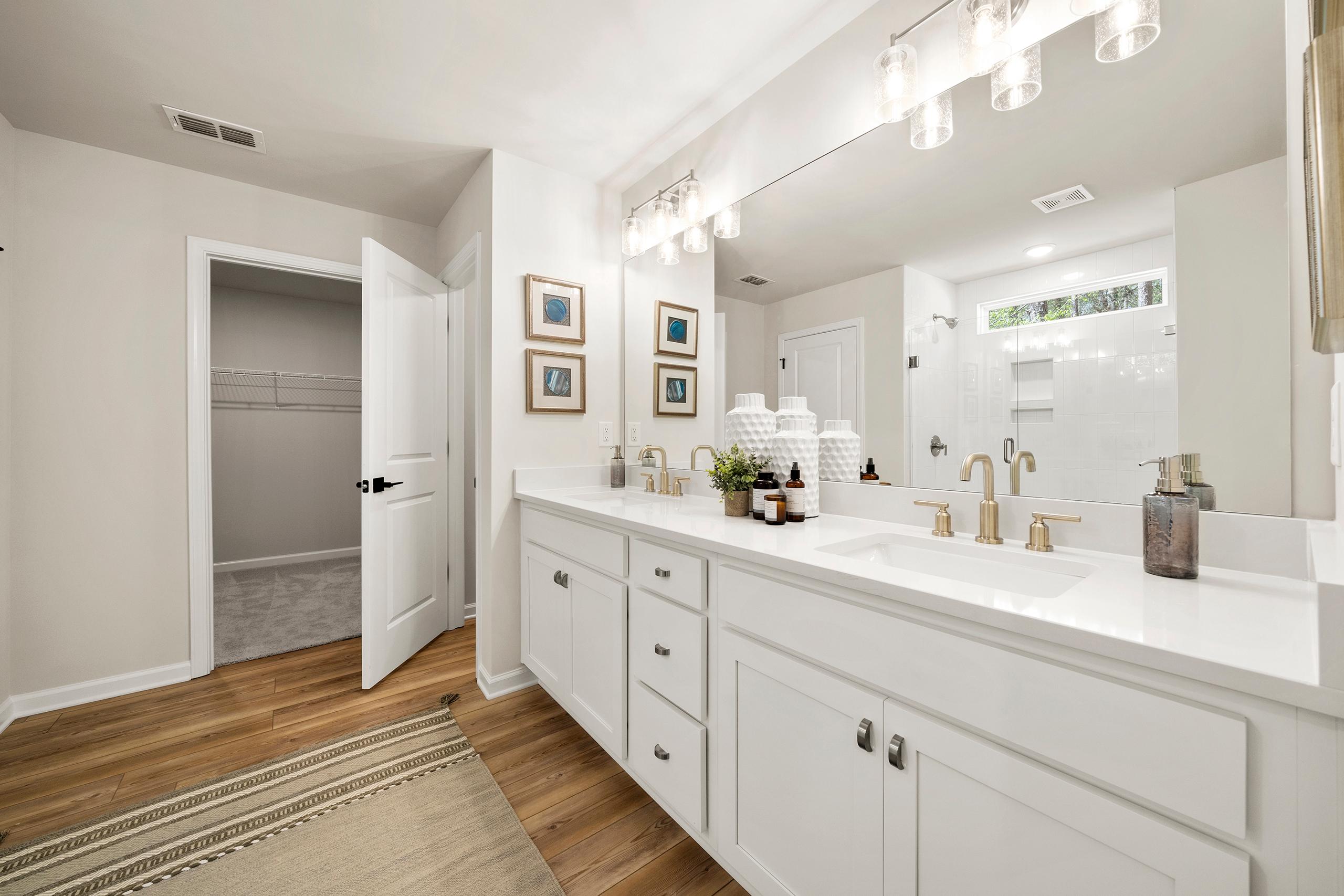 Spacious primary bathroom at Reverie at East Lake in McDonough GA with double vanity, walk-in closet, and glass shower
