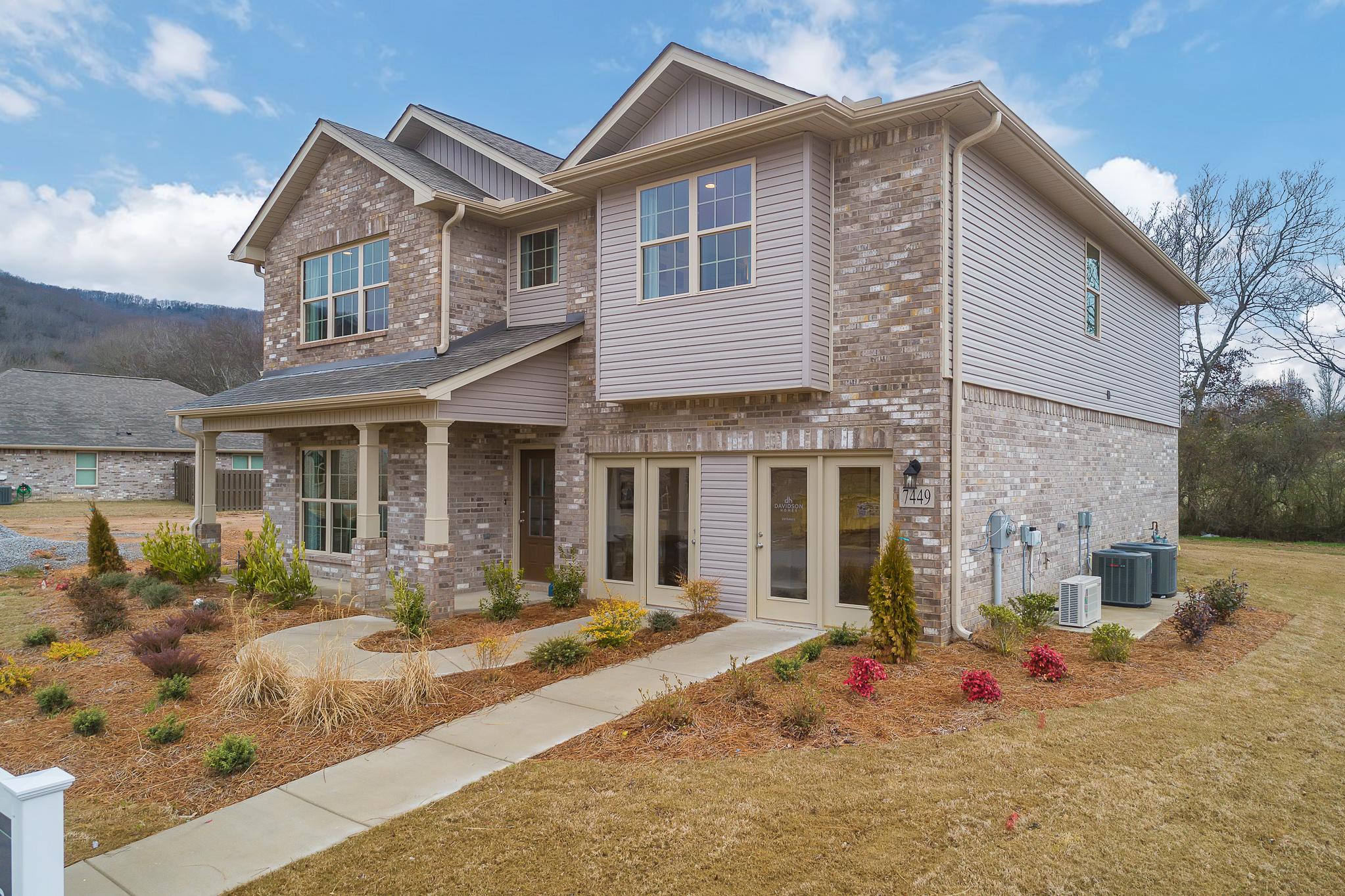 Two-story brick home exterior at The Reserve at Overton in Hampton Cove, Alabama with covered front porch and landscaped yard
