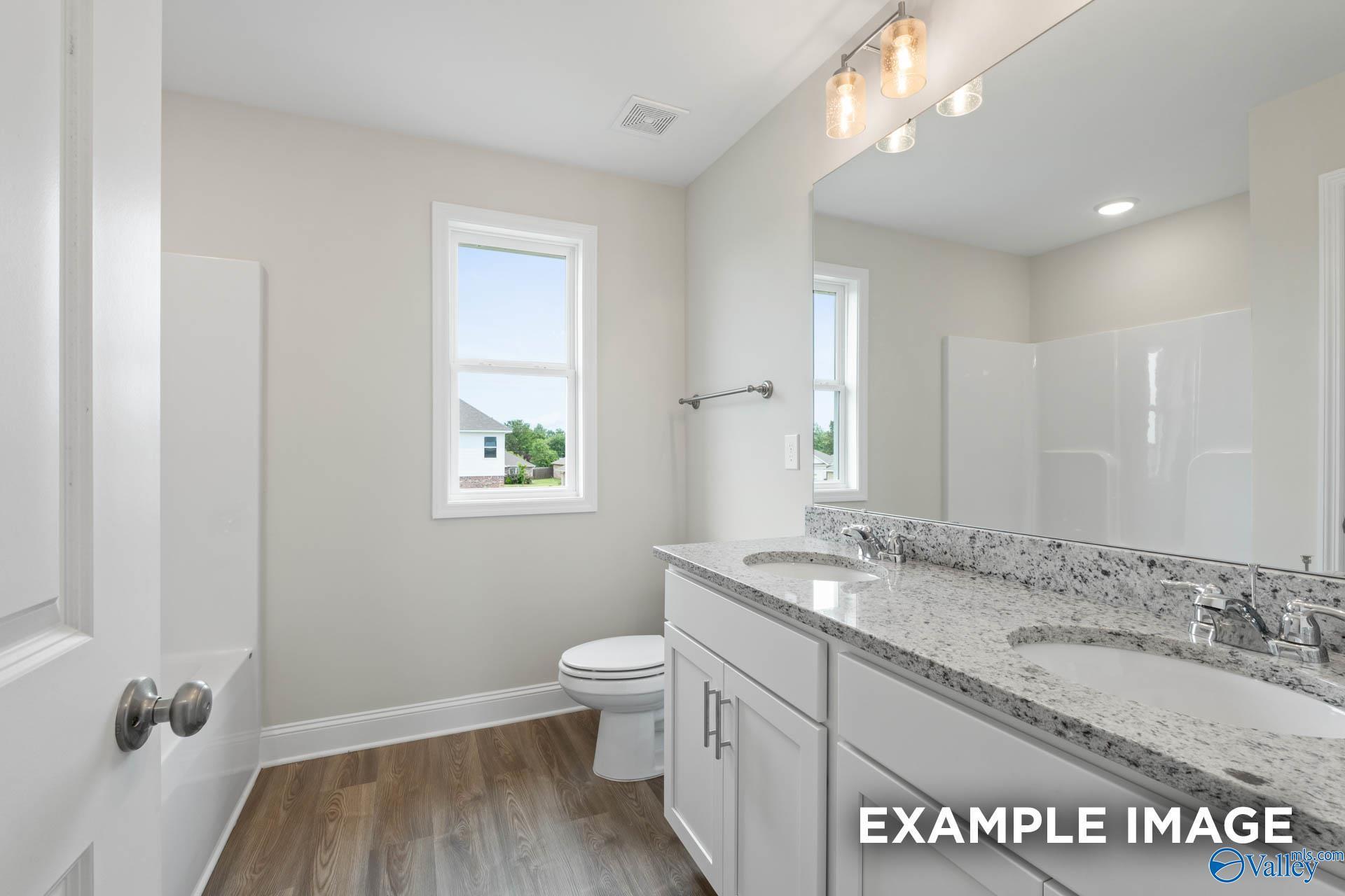Modern bathroom with dual vanity, granite countertops, and tub-shower combo in The Shelby B home, Jaguar Hills, Huntsville.