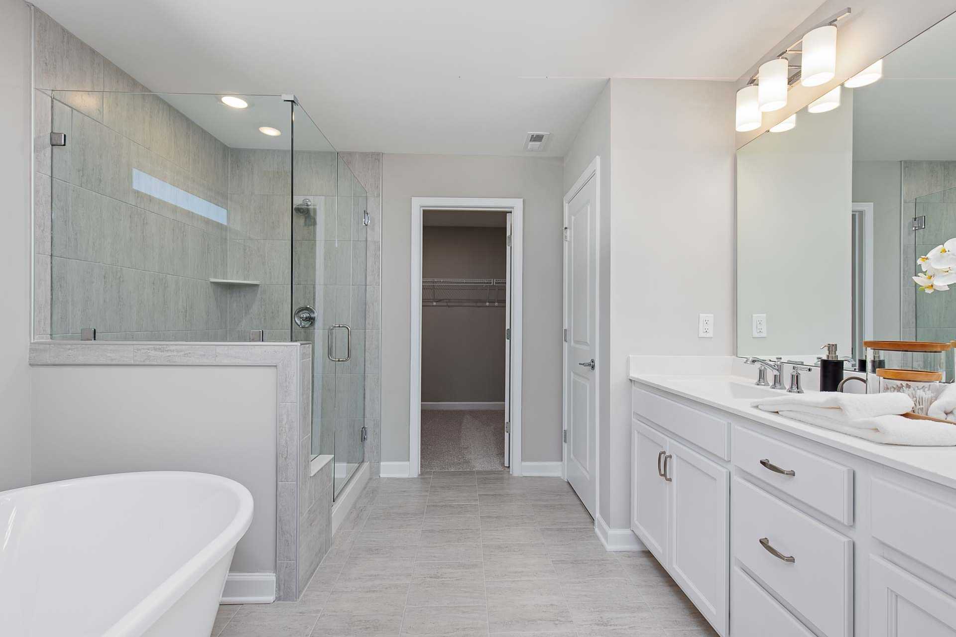 Luxurious primary bathroom in Highland Forest Fuquay-Varina NC with freestanding tub, glass shower, and double vanity by Davidson Homes