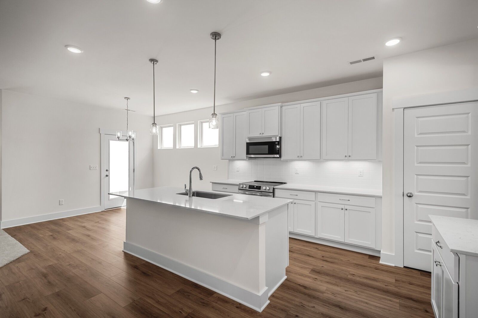 Modern kitchen with quartz island and white cabinets in The Ash A floor plan at Woods Crossing in Gallatin, Tennessee.