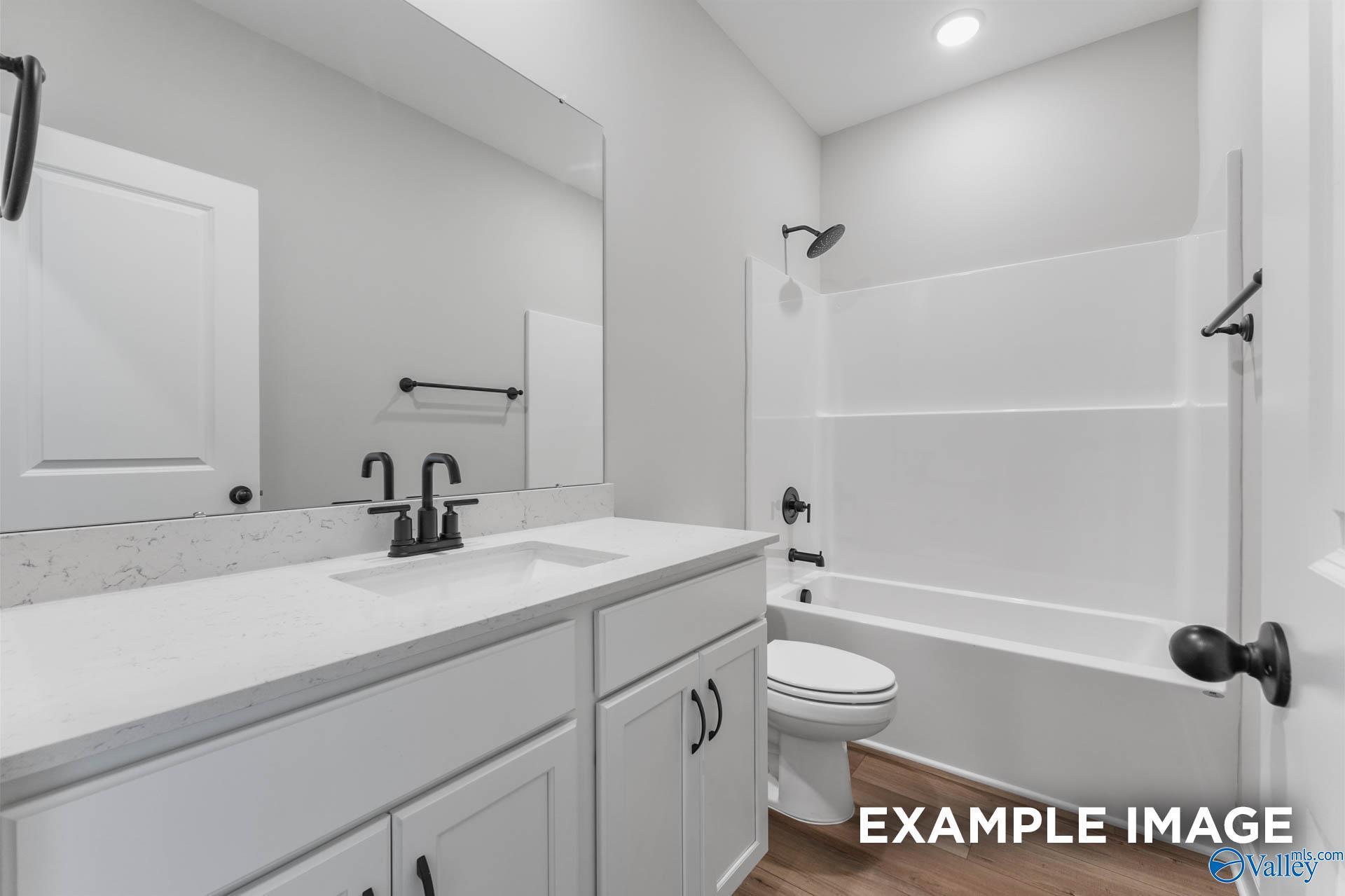 Modern secondary bathroom with white double vanity, quartz counters, tub-shower combo in Davidson Homes The Daphne C, Athens AL