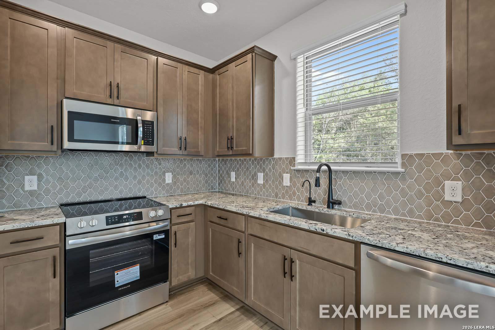 Modern kitchen with granite countertops, stainless appliances, and honeycomb tile backsplash in Davidson Homes Florence A.