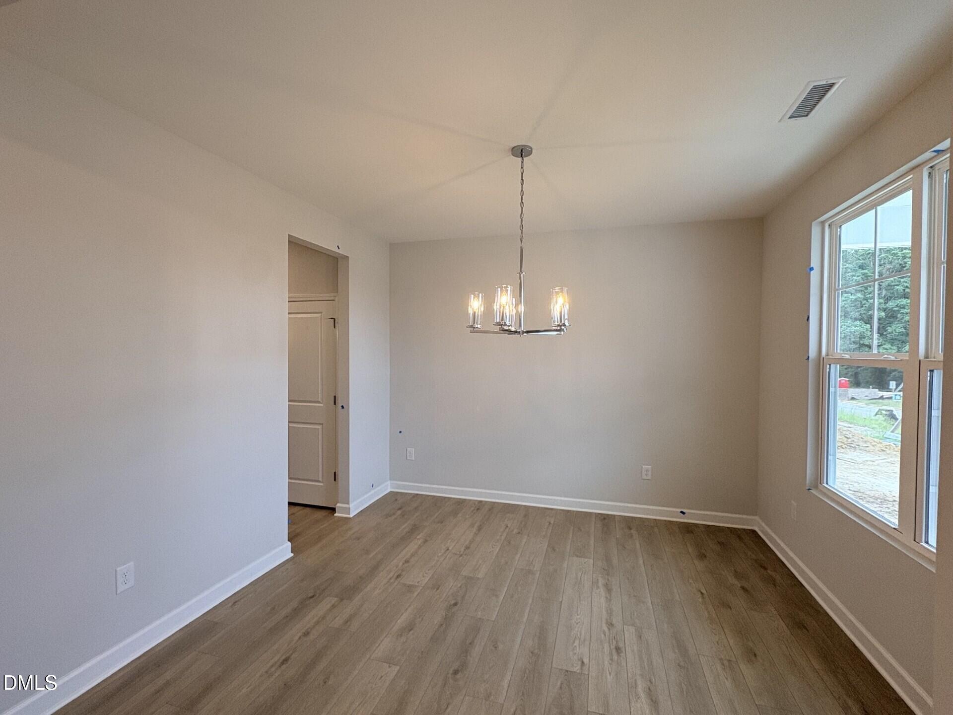 Bright dining room with luxury vinyl plank flooring, modern chandelier, and large window in Davidson Homes The Ash C, Zebulon, NC