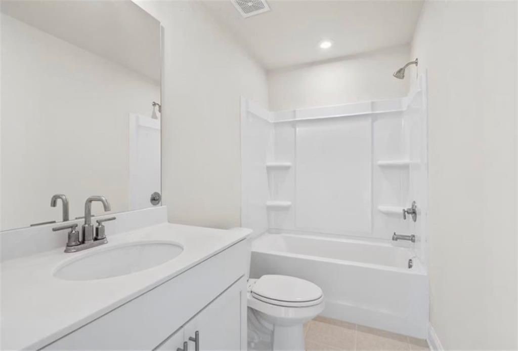 Modern full bathroom with white vanity and tub-shower combo in The Ash C floor plan at Wehunt Meadows, Hoschton, Georgia.