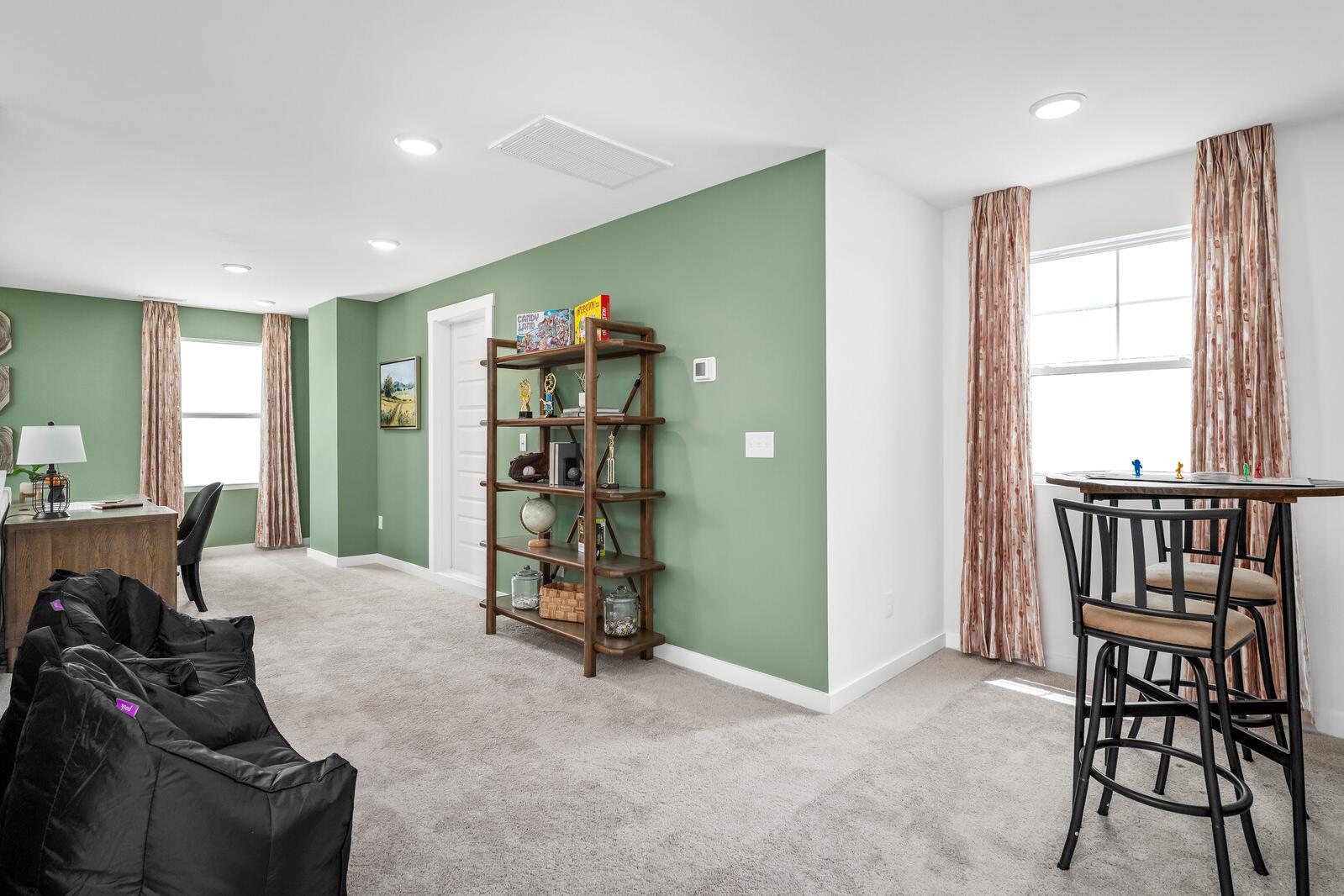 Cozy loft bonus room at Calista Farms in White House TN with sage green wall, bookshelves, desk, bar stools and bean bag seating