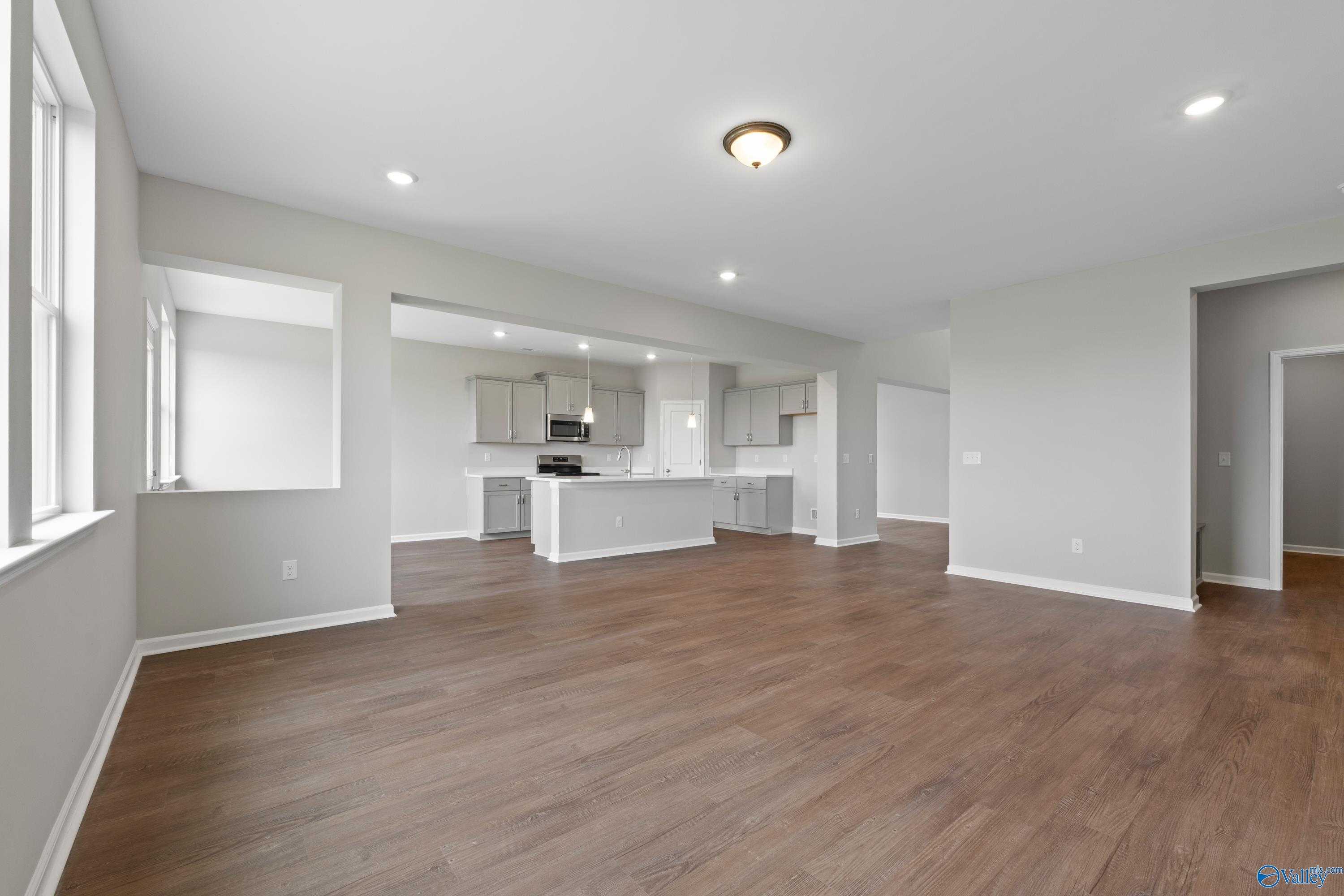 Open-concept kitchen with white shaker cabinets, center island, hardwood floors, and large windows in Davidson Homes The Dorado, Athens AL