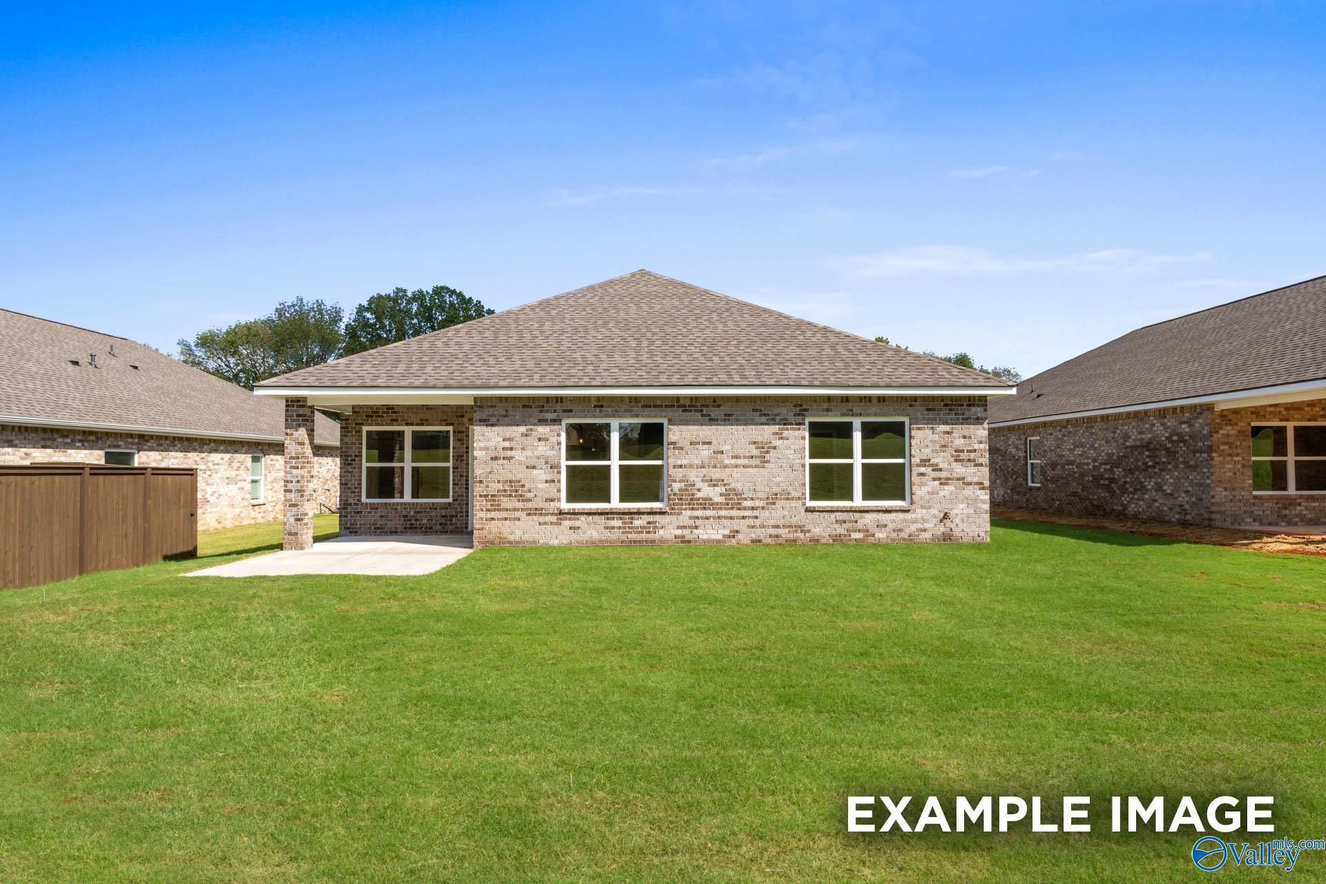 Single-story brick Daphne D home with gabled roof, large windows, concrete patio, lush green yard, and privacy fence in Walker's Hill, Meridianville, Alabama