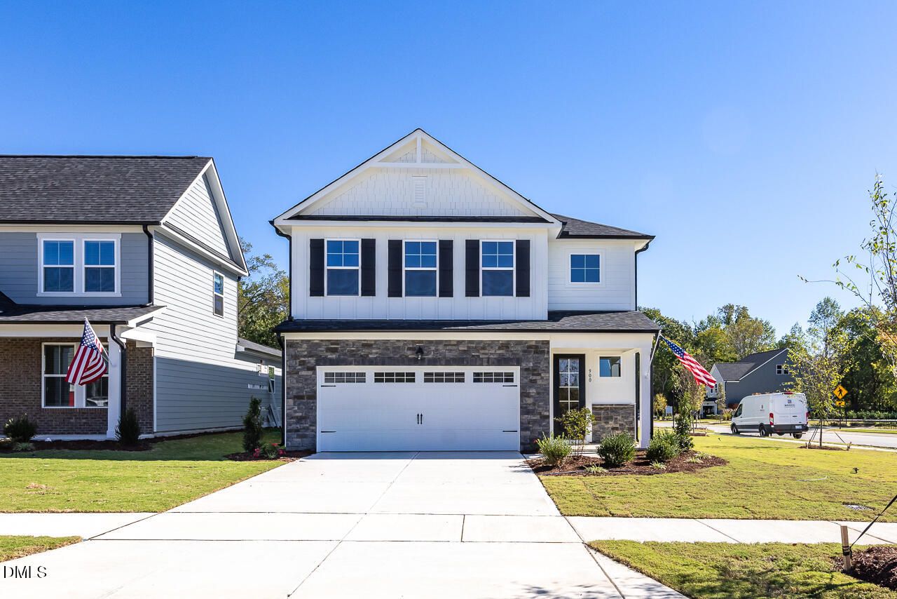 Two-story white new construction home with stone accents, 2-car garage, and American flag in Wendell Ridge, Wendell, North Carolina