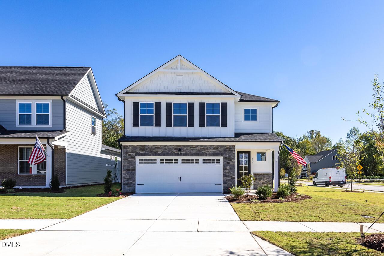 Two-story white new construction home with stone accents, 2-car garage, and American flag in Wendell Ridge, Wendell, North Carolina