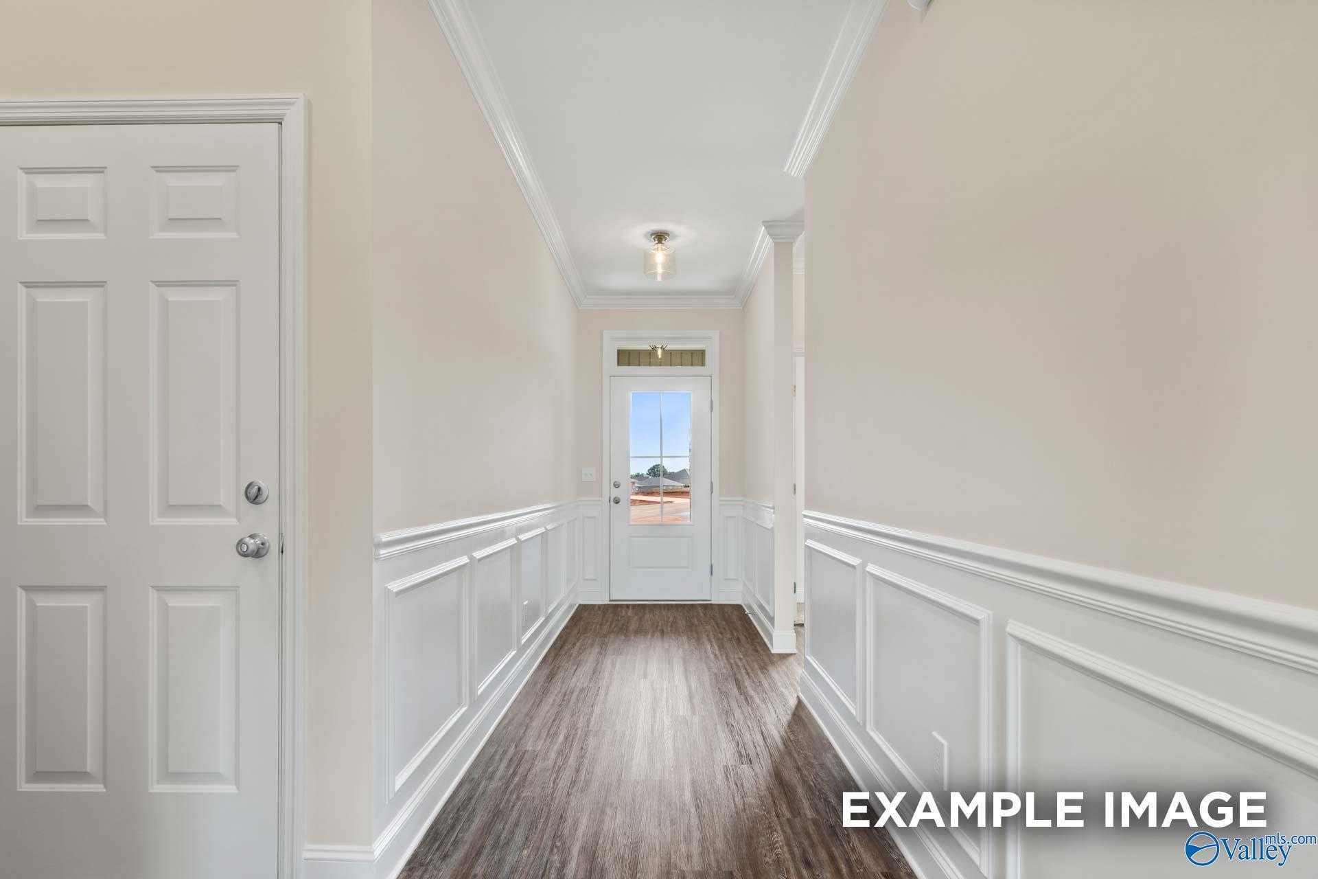 Elegant hallway with wainscoting, hardwood floors and white doors in The Asheville 3-bedroom home by Davidson Homes, Arab, Alabama