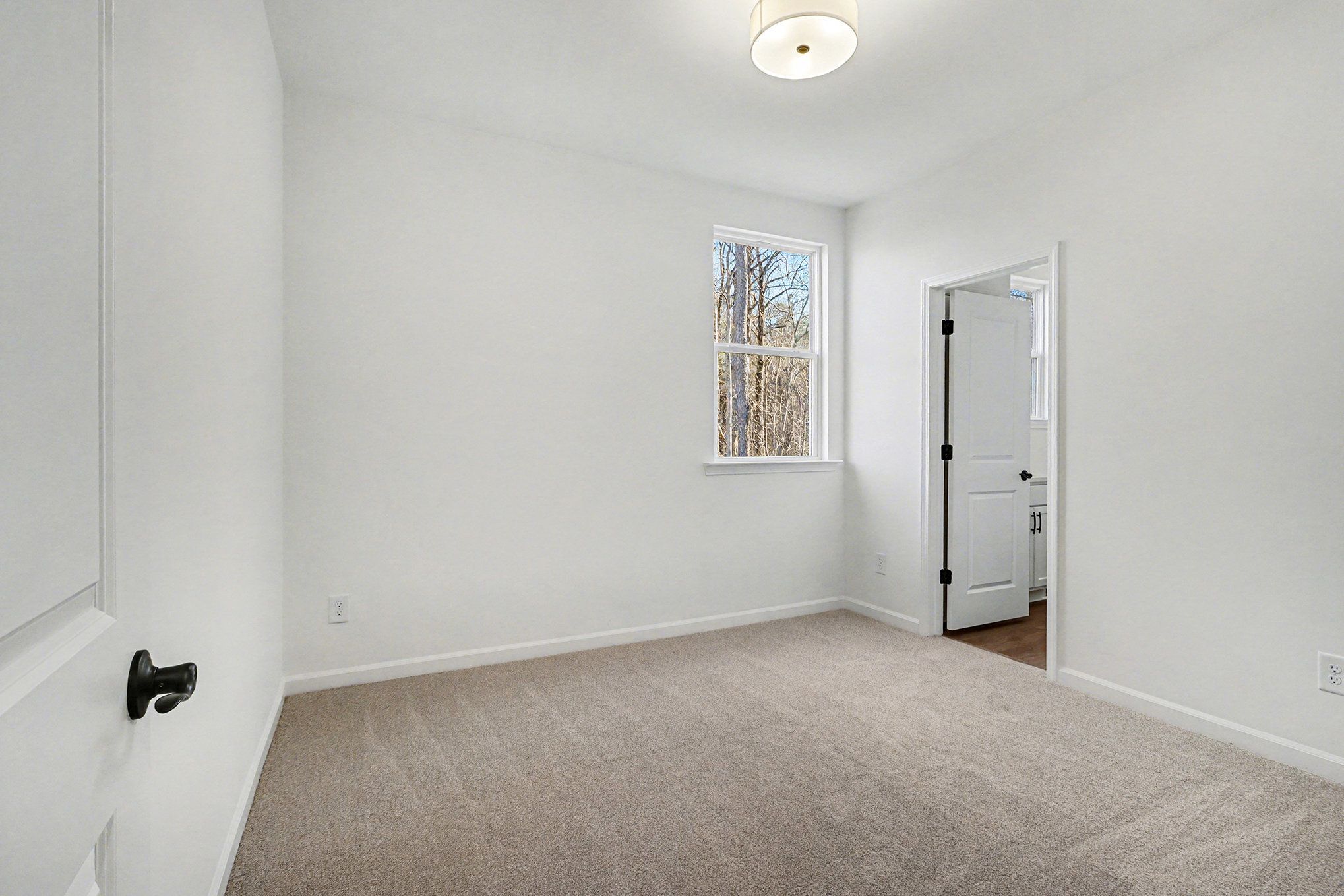 Bright secondary bedroom with beige walls, gray carpet, window blinds, and bath access in The Daphne B, Loganville, GA