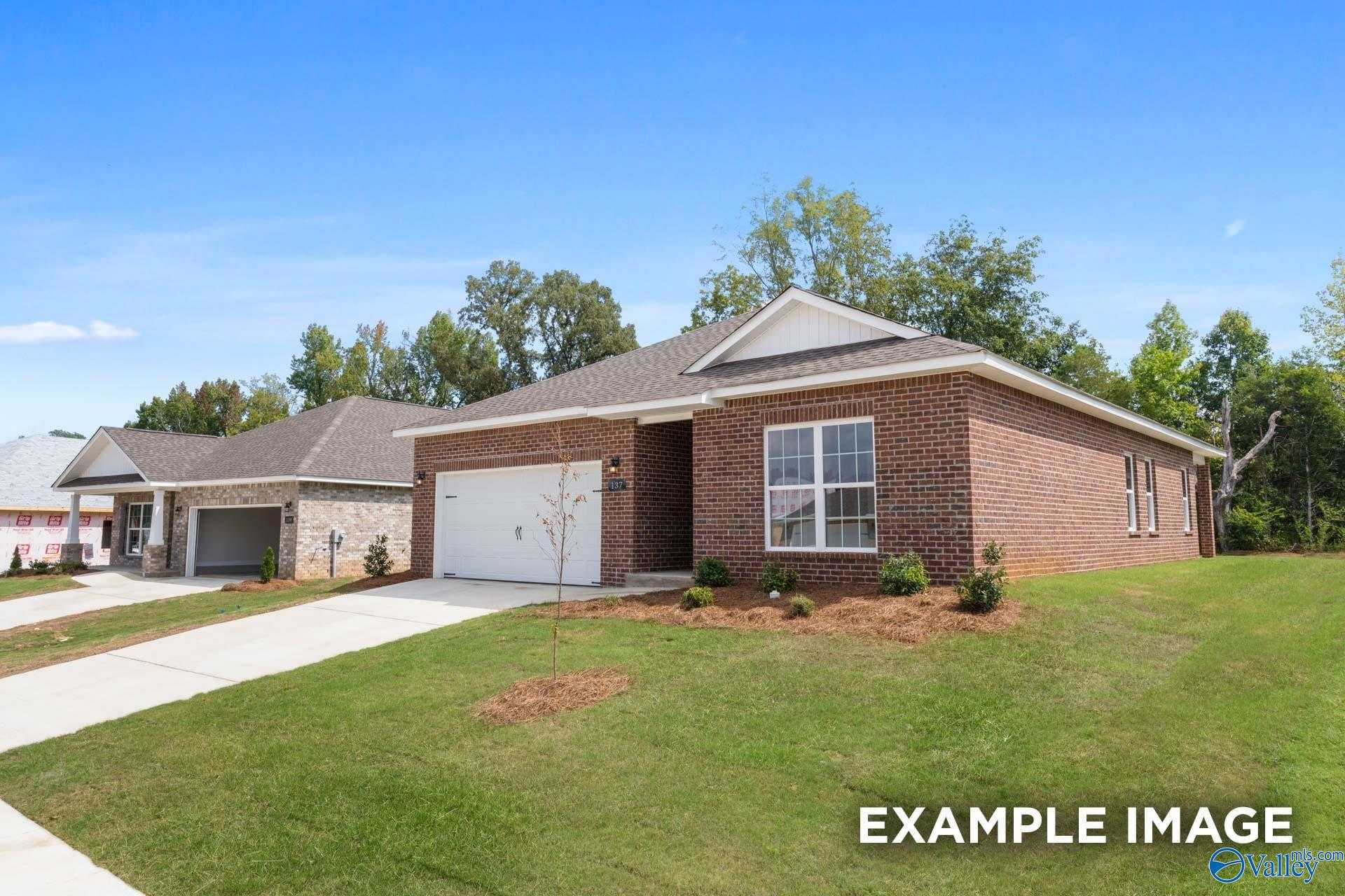 Single-story brick ranch home with 2-car garage, driveway, and landscaped yard in Heritage Lakes, New Market, Alabama