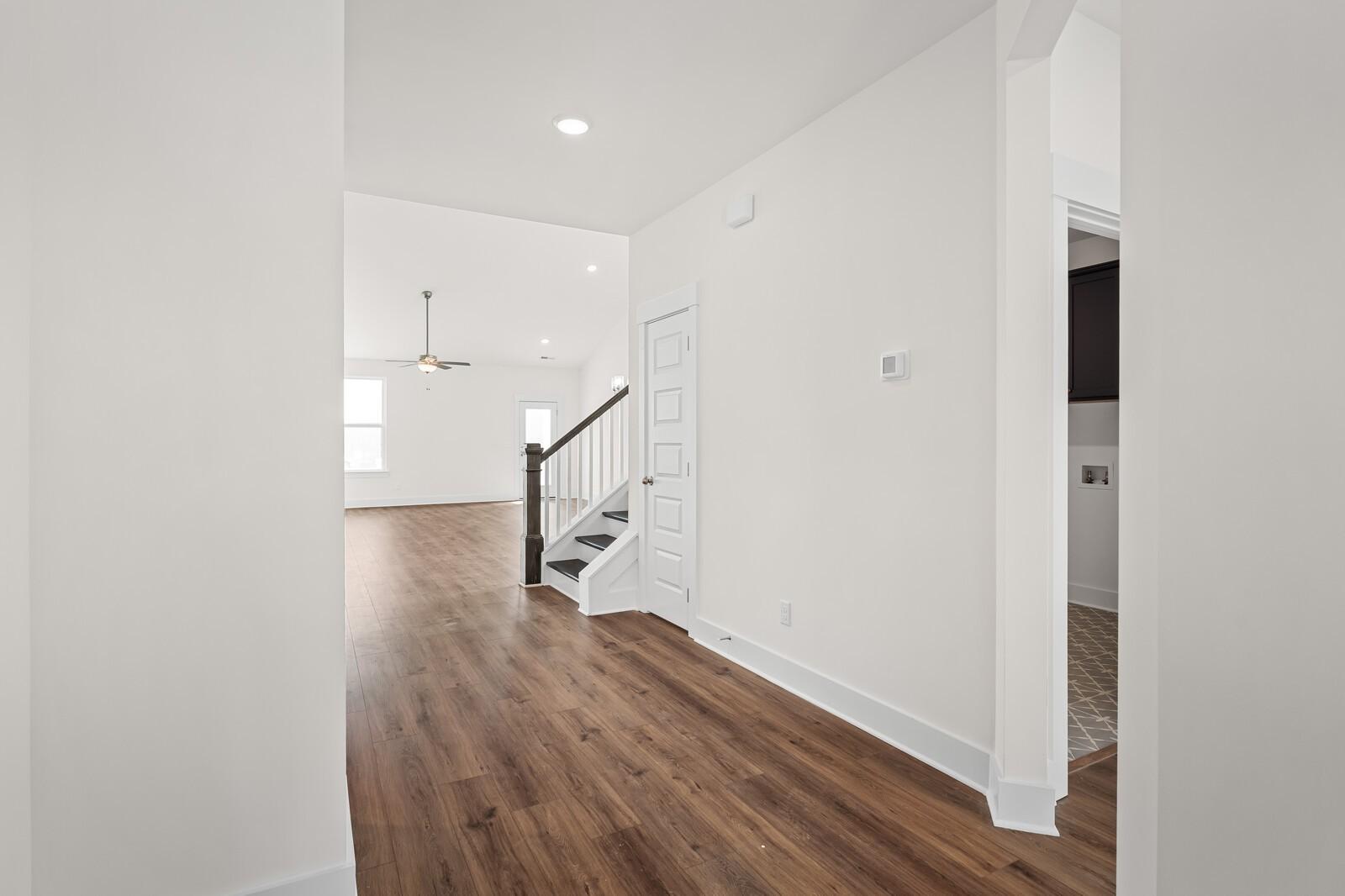 Bright foyer with hardwood floors, white walls, and curved staircase in Davidson Homes Ridgeport, Gallatin, TN