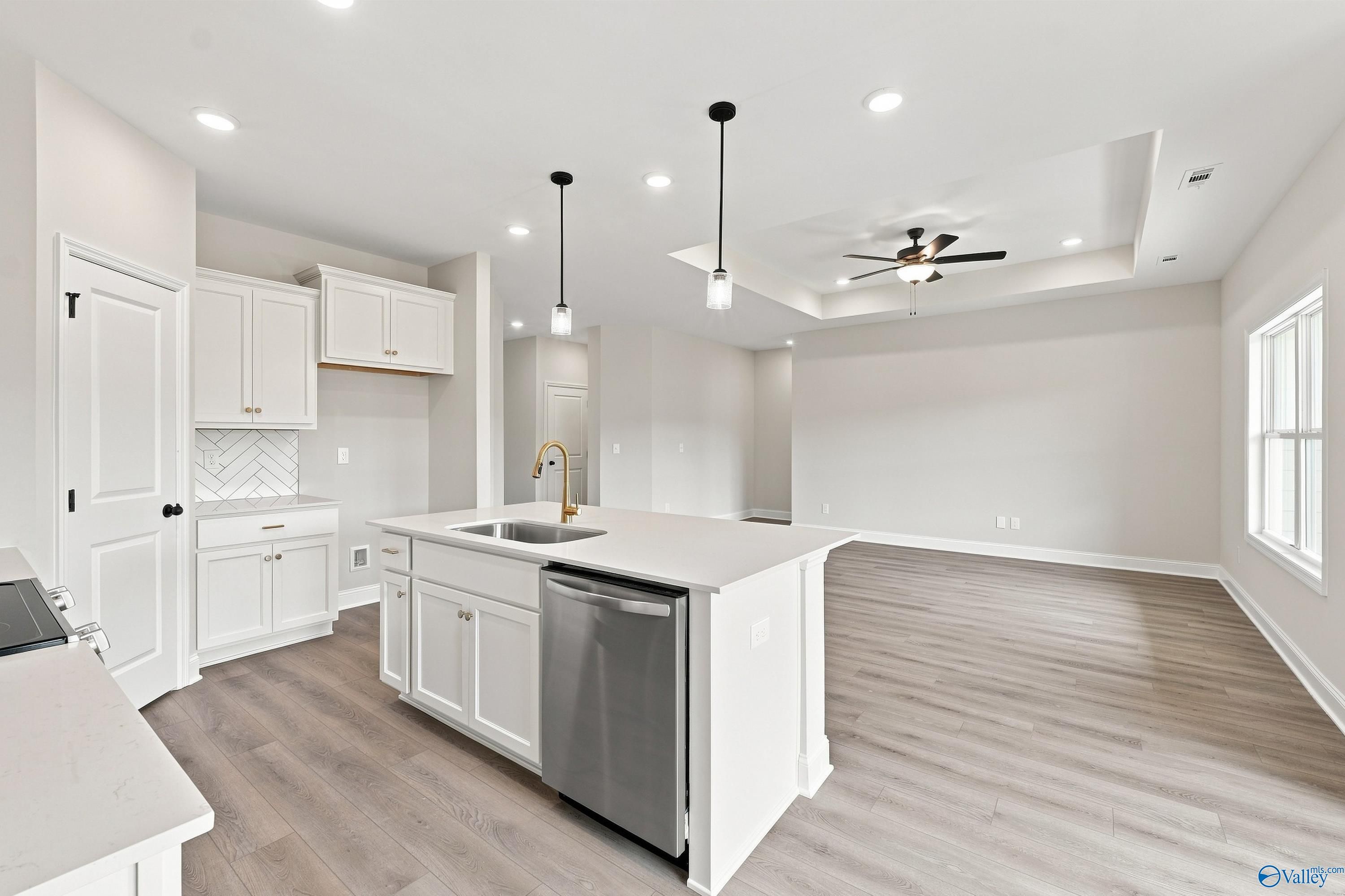 Open-concept kitchen with white cabinets and island in The Asheville E floor plan at Forest Glen, Hazel Green, Alabama.