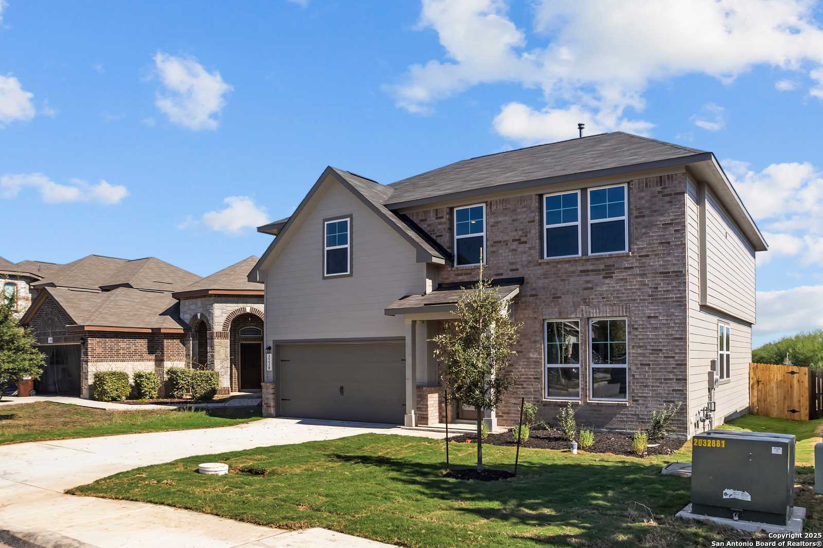 Two-story beige brick home with 2-car garage, driveway, and landscaped yard in Horizon Pointe, Converse, Texas