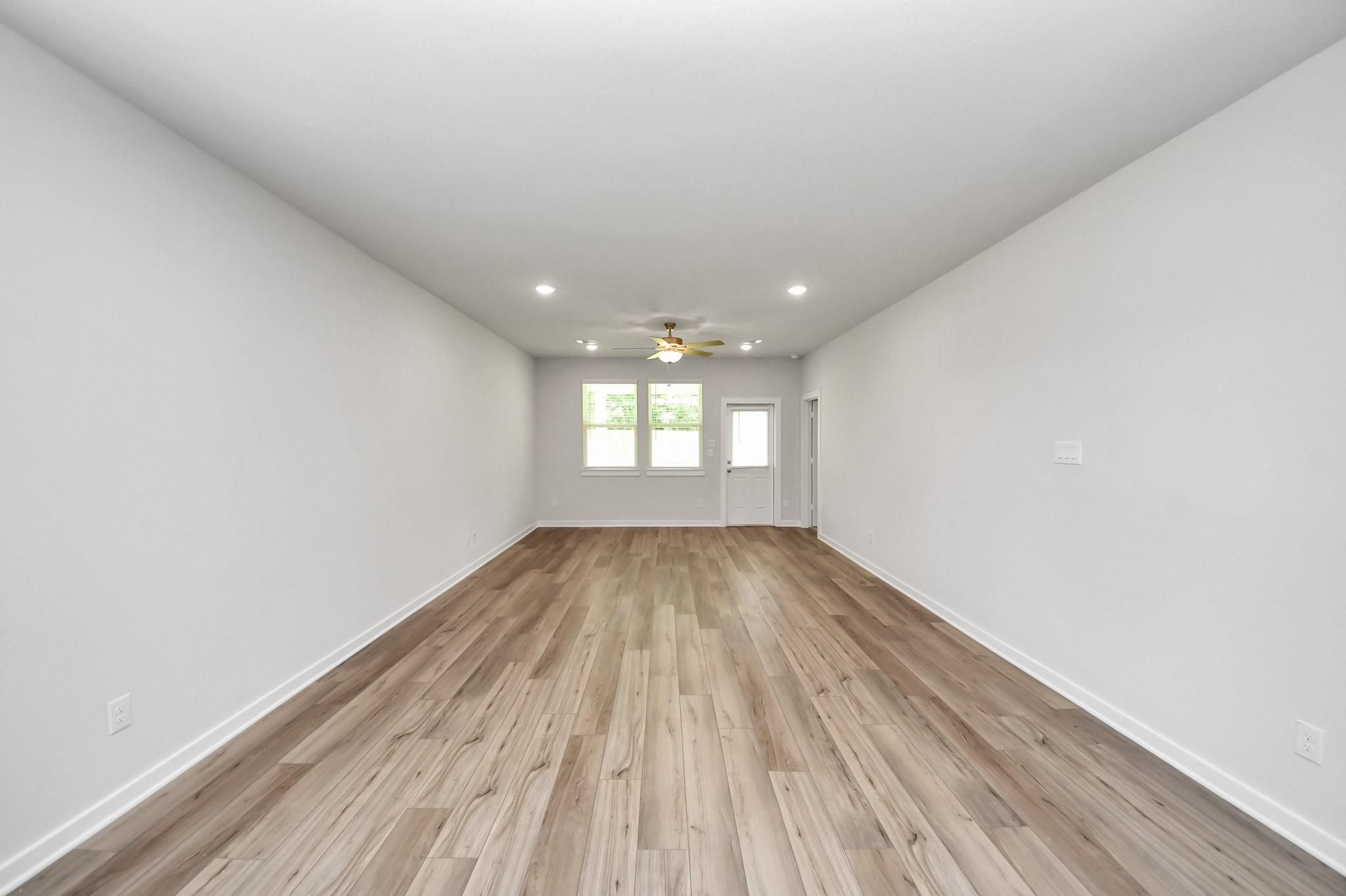 Spacious open-concept living area with wood-look flooring in The Sabine E floor plan at Liberty Estates, Cleveland, Texas.