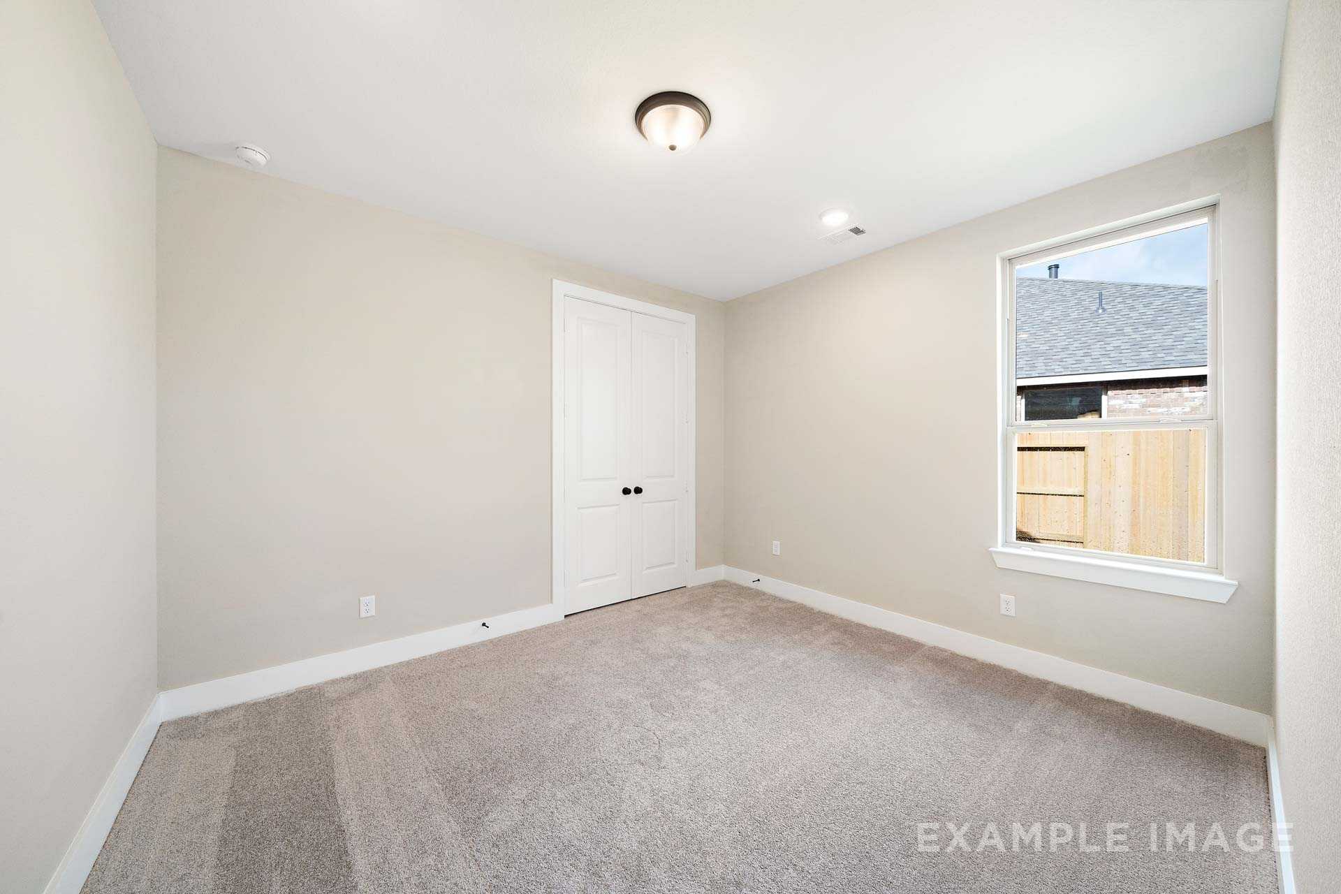 Spacious secondary bedroom in The Elizabeth A Davidson Homes design, beige walls, carpeted floor, large window overlooking backyard