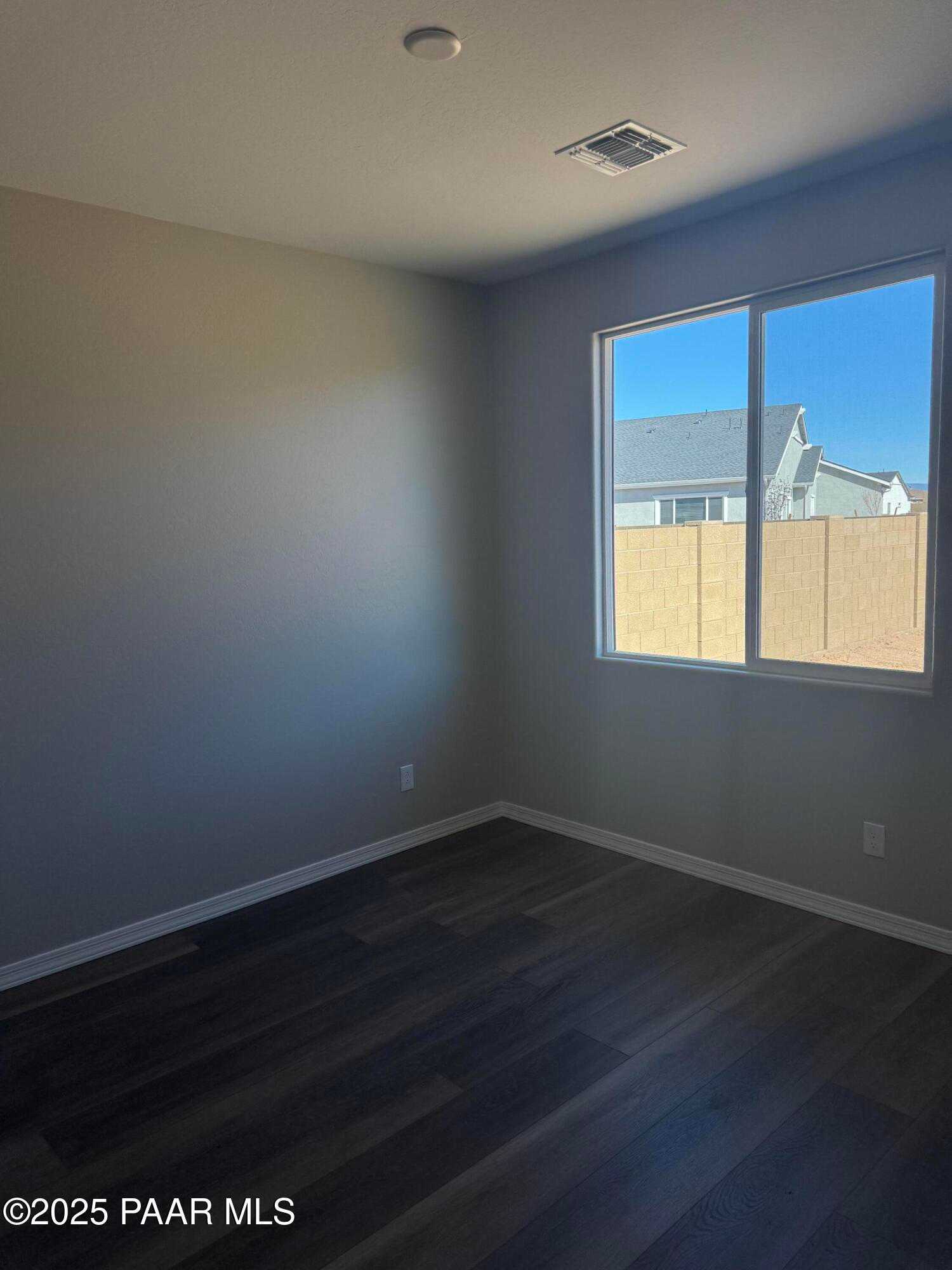 Bright secondary bedroom with large window, hardwood floors, and backyard view in Davidson Homes The Monarch E, Prescott AZ