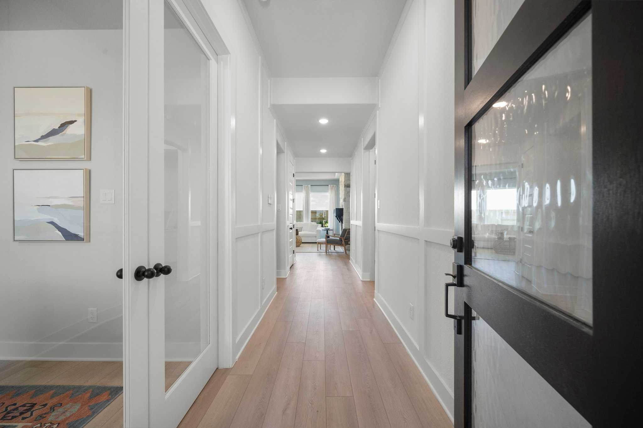 Bright hallway in Lago Mar home by Davidson Homes, Texas City TX with oak hardwood floors, white wainscoting, and glass doors