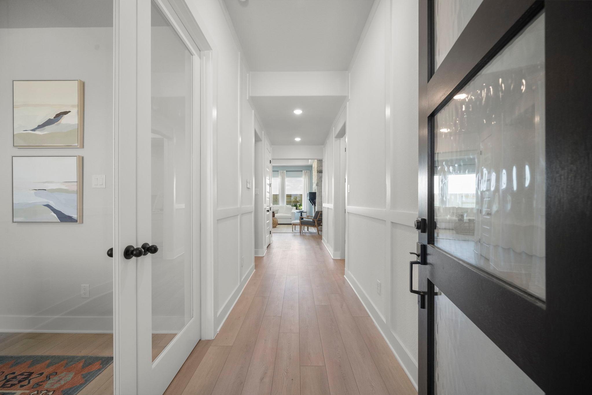 Bright hallway in Lago Mar home by Davidson Homes, Texas City TX with oak hardwood floors, white wainscoting, and glass doors