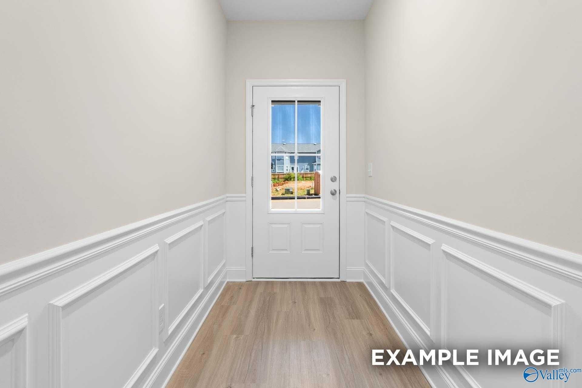 Bright hallway with white wainscoting, hardwood floors, and glass door to backyard in Davidson Homes The Camden C, Huntsville