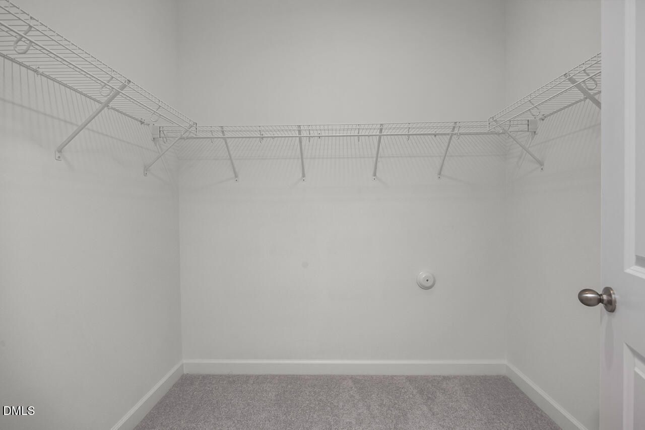 Walk-in closet with white wire shelving in The Ashport G floor plan at Sage on North Main, Wake Forest, North Carolina.