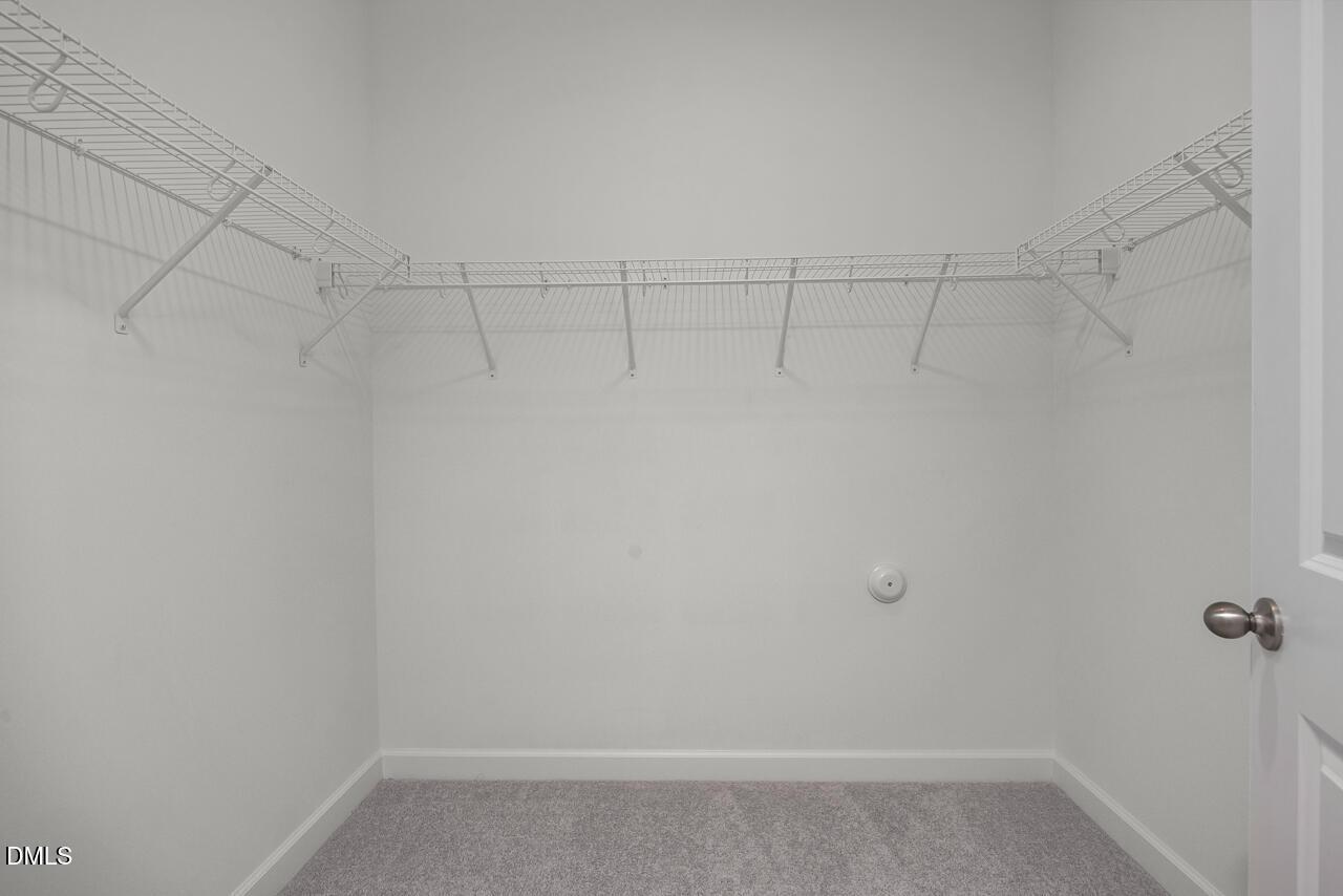 Walk-in closet with white wire shelving in The Ashport G floor plan at Sage on North Main, Wake Forest, North Carolina.