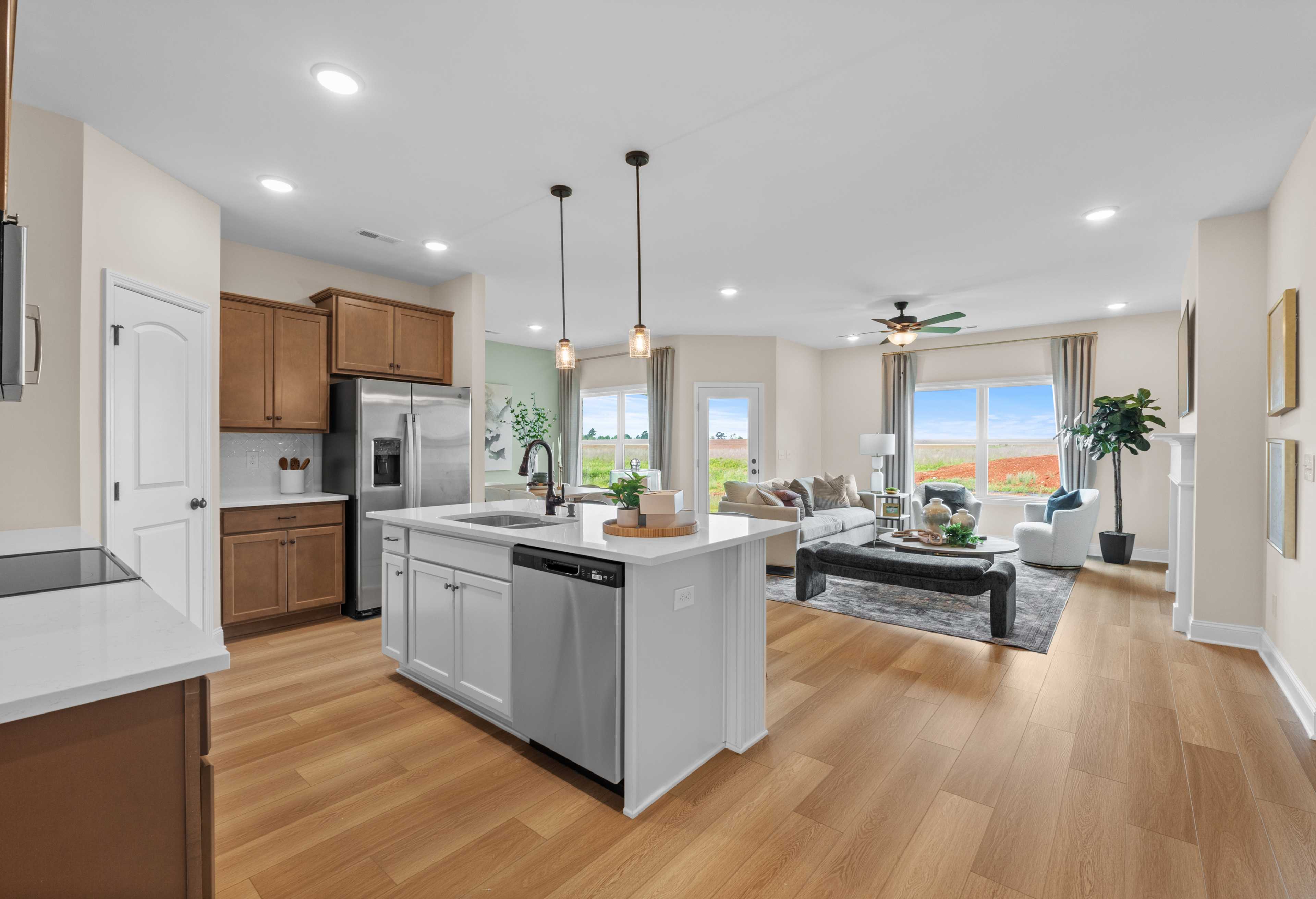 Spacious open-concept kitchen and living area in The Daphne F featuring large island, stainless appliances, and ample windows