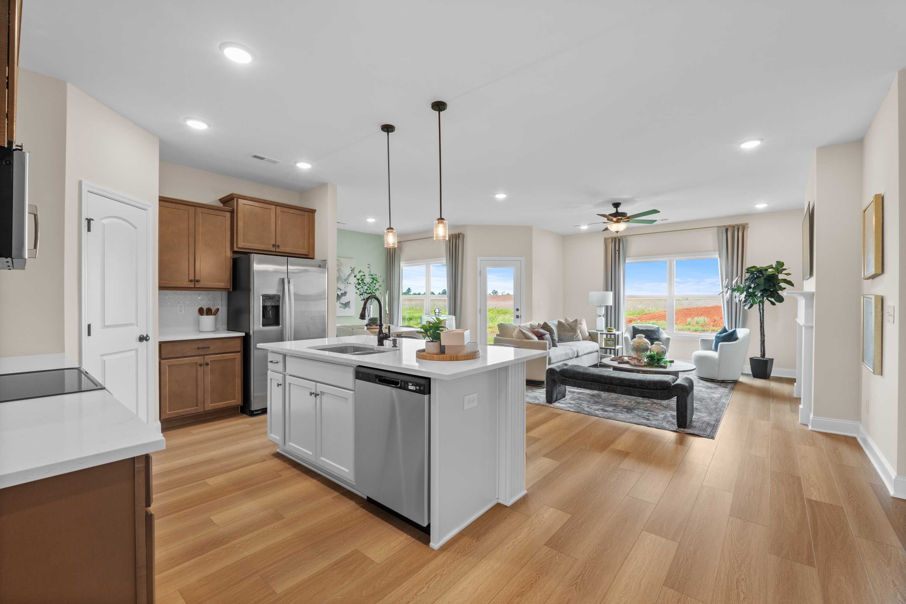 Spacious open-concept kitchen and living area in The Daphne F featuring large island, stainless appliances, and ample windows