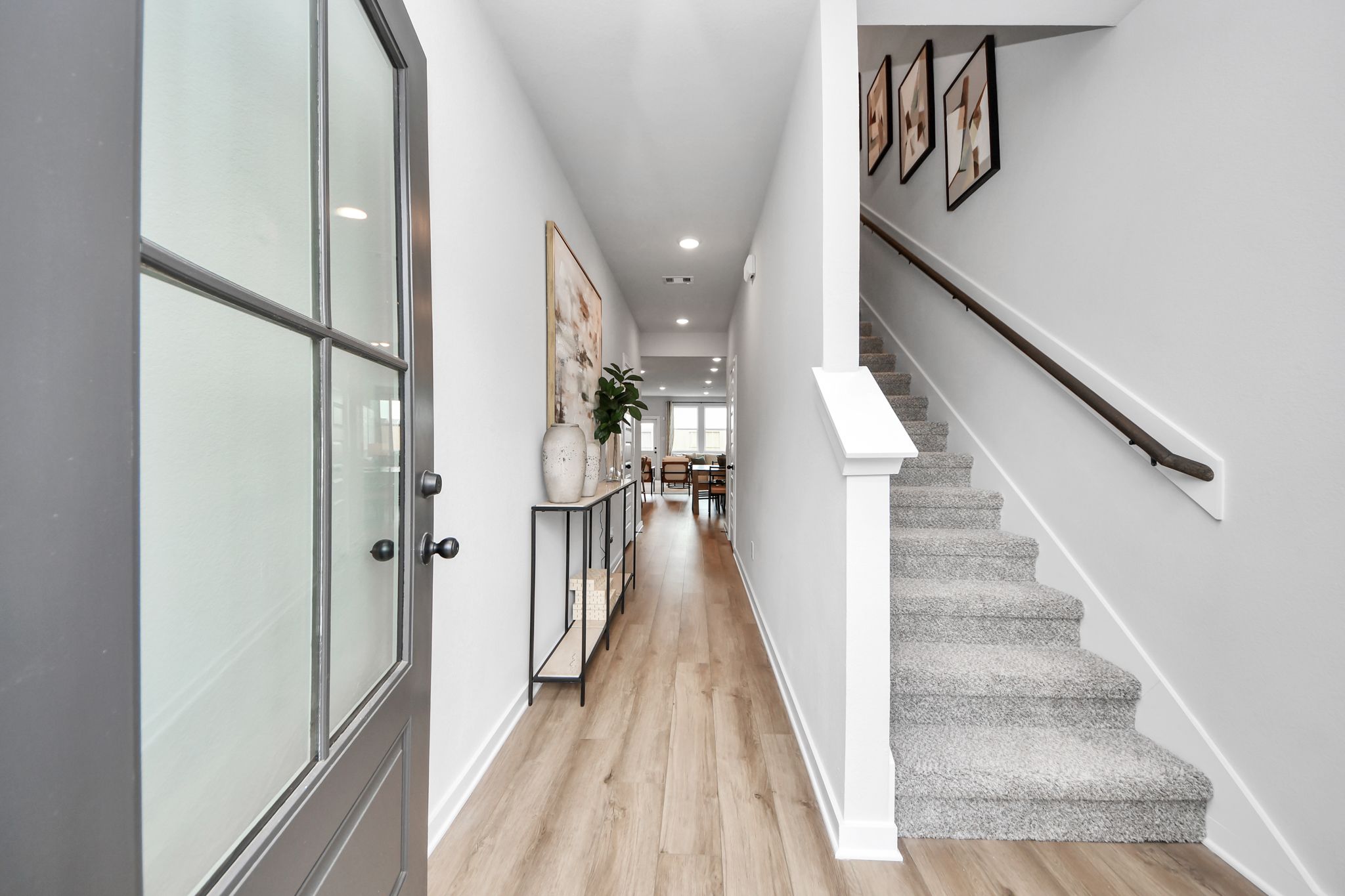 Bright entryway at Robins Landing in Houston, TX by Davidson Homes with wood flooring and carpeted staircase.