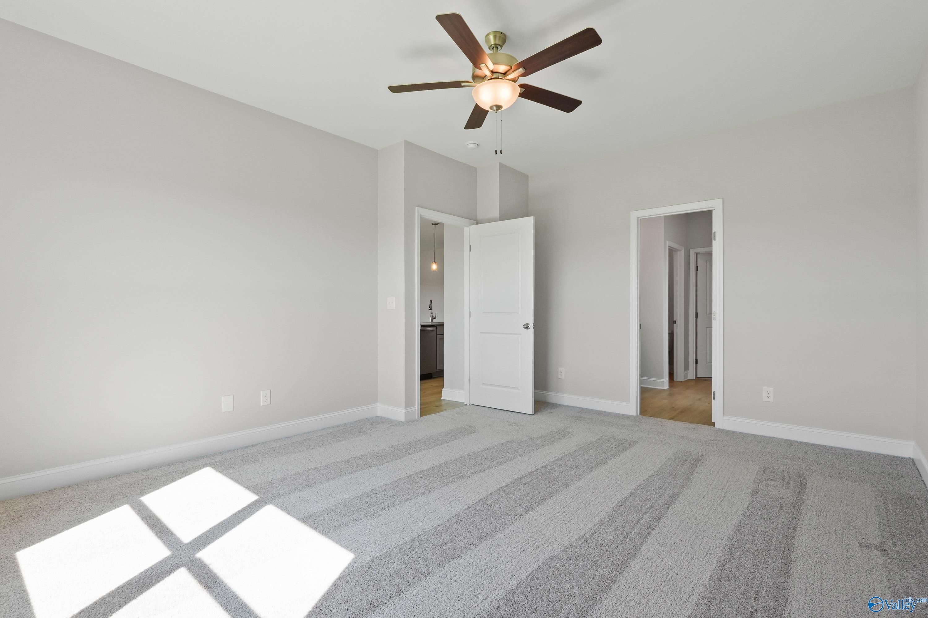 Bright bedroom with gray carpet, ceiling fan, and adjacent bath in Davidson Homes The Everett, Hazel Green, AL