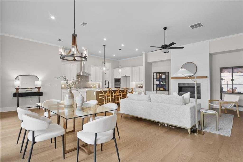 Open-concept living-dining area with white sofa, glass table, gourmet kitchen, and fireplace in The Seaside B by Davidson Homes, Woodstock, GA