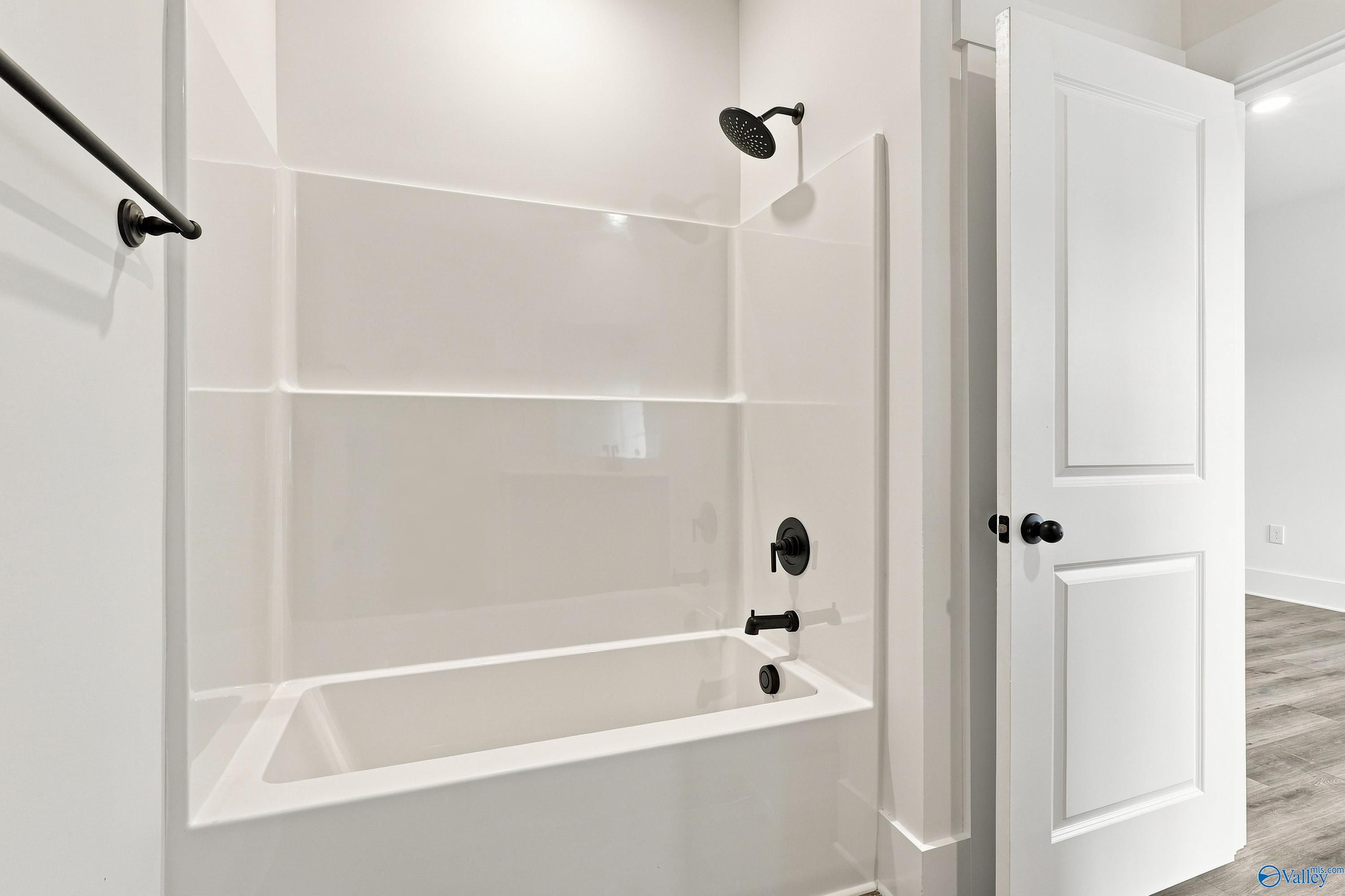 White tub shower combo with matte black fixtures in bathroom of Davidson Homes The Valencia, Riverton Preserve, Huntsville