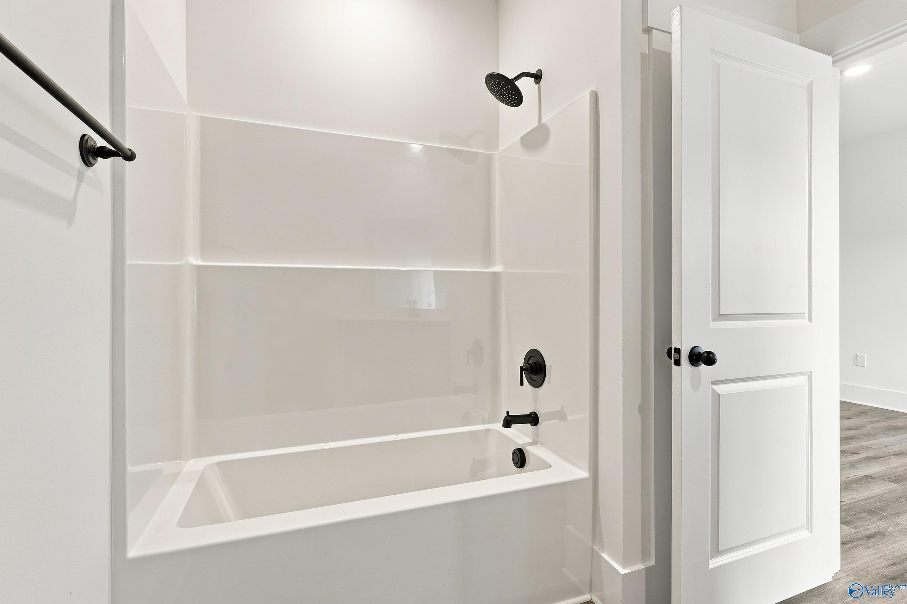 White tub shower combo with matte black fixtures in bathroom of Davidson Homes The Valencia, Riverton Preserve, Huntsville