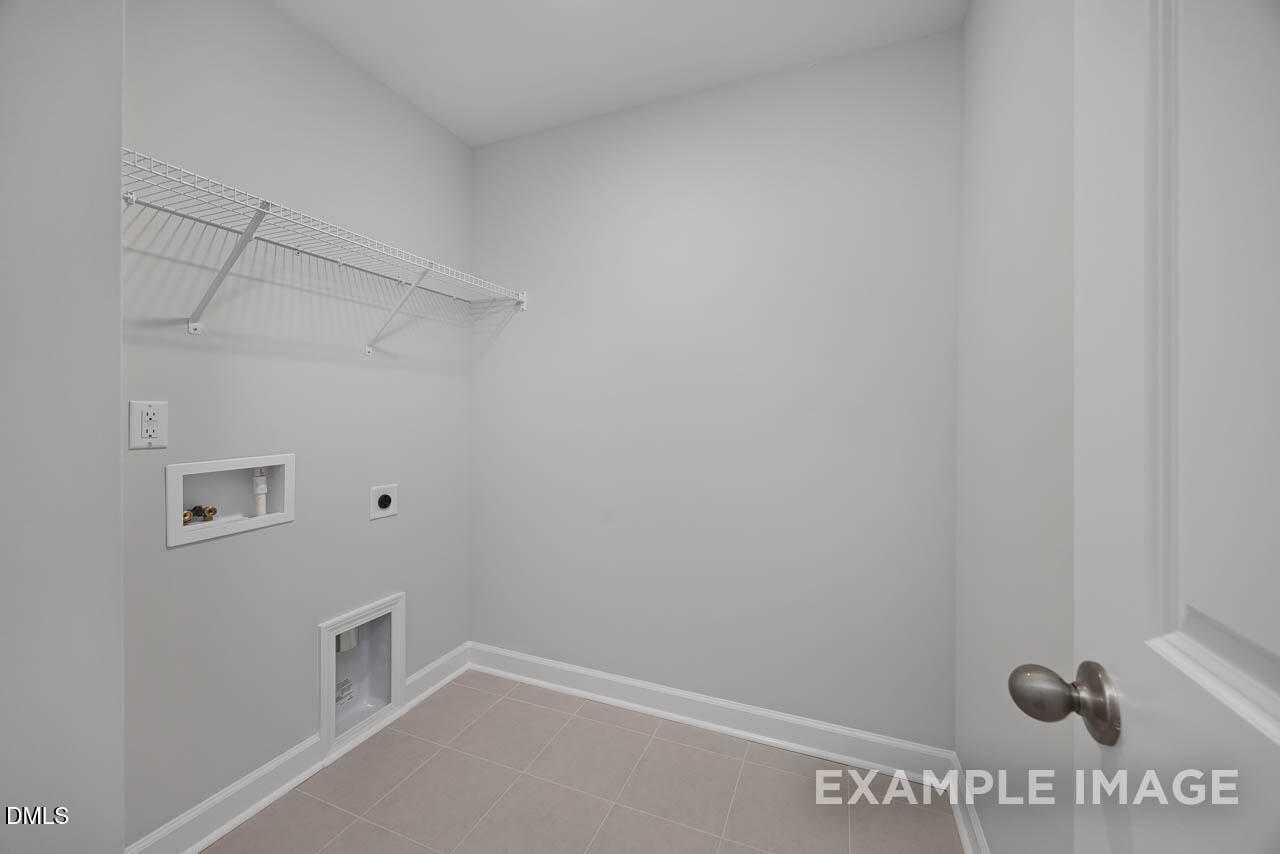 Modern laundry room with wire shelving, washer/dryer hookups and tiled floor in Davidson Homes The Warren, Fuquay-Varina, NC