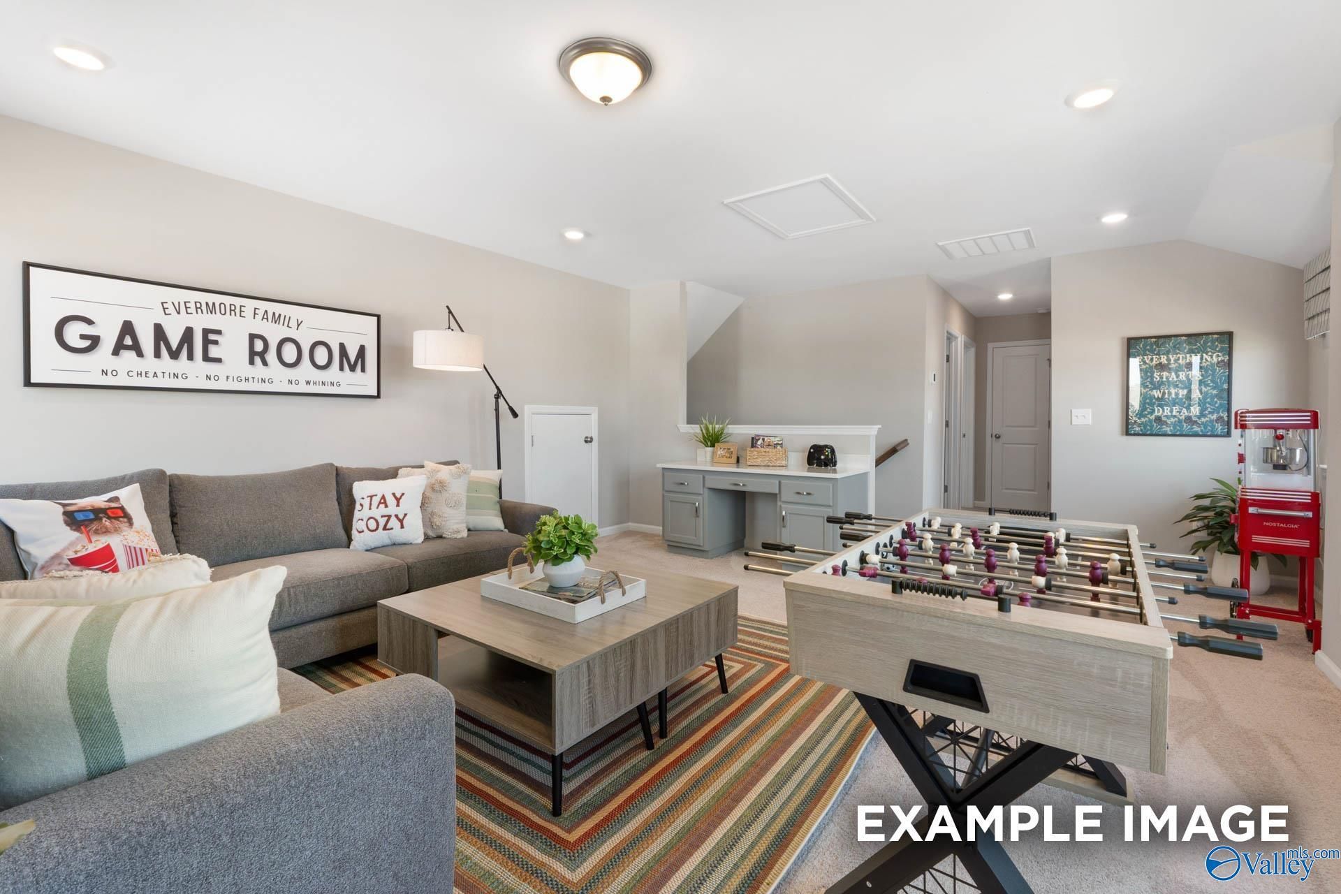 Cozy game room with foosball table, gray sofa, and "GAME ROOM" sign in Davidson Homes The Stella, Madison, Alabama