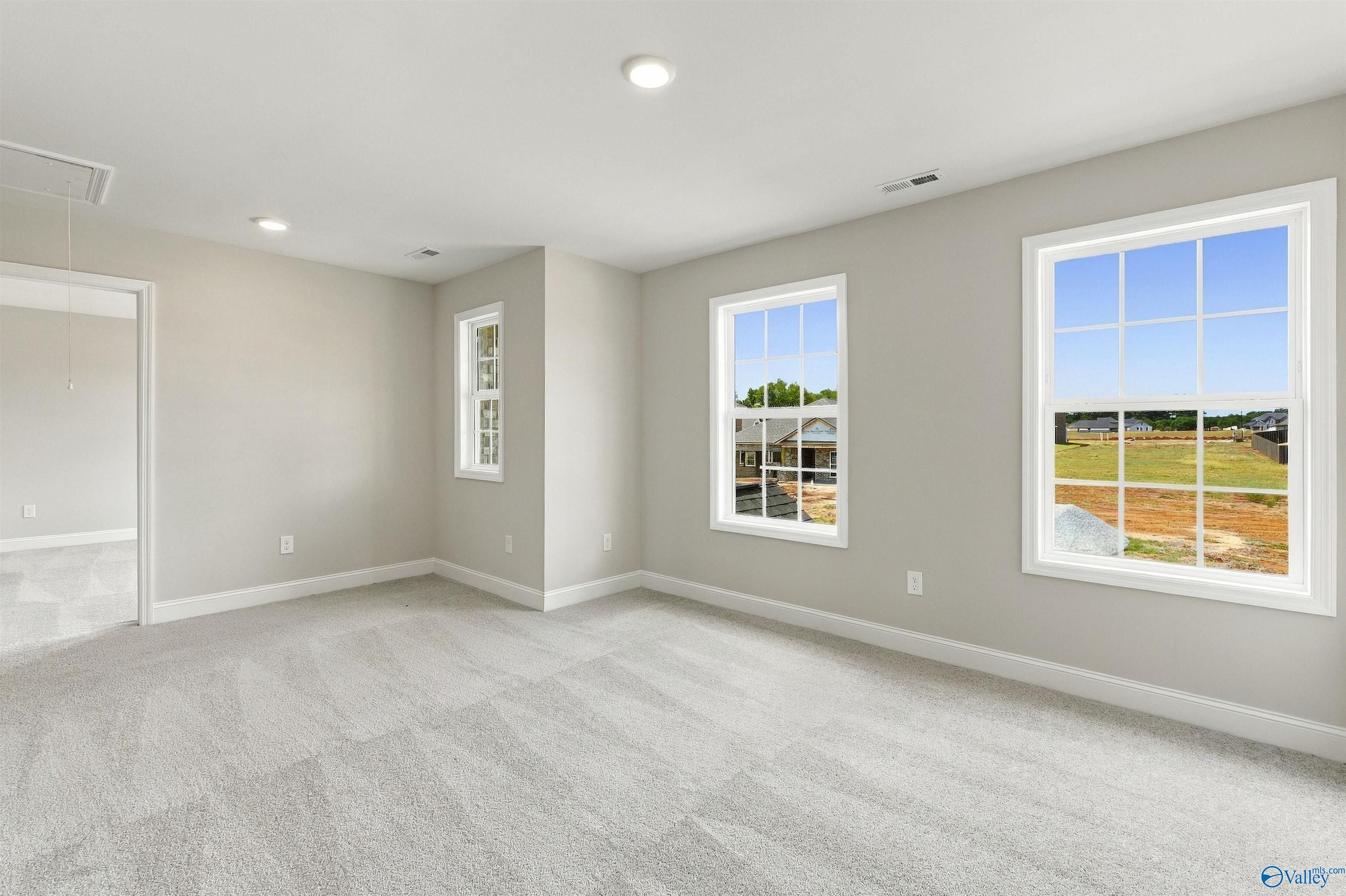Bright carpeted bedroom with large windows overlooking The Meadows neighborhood in Davidson Homes' Shelby A plan, Athens, Alabama
