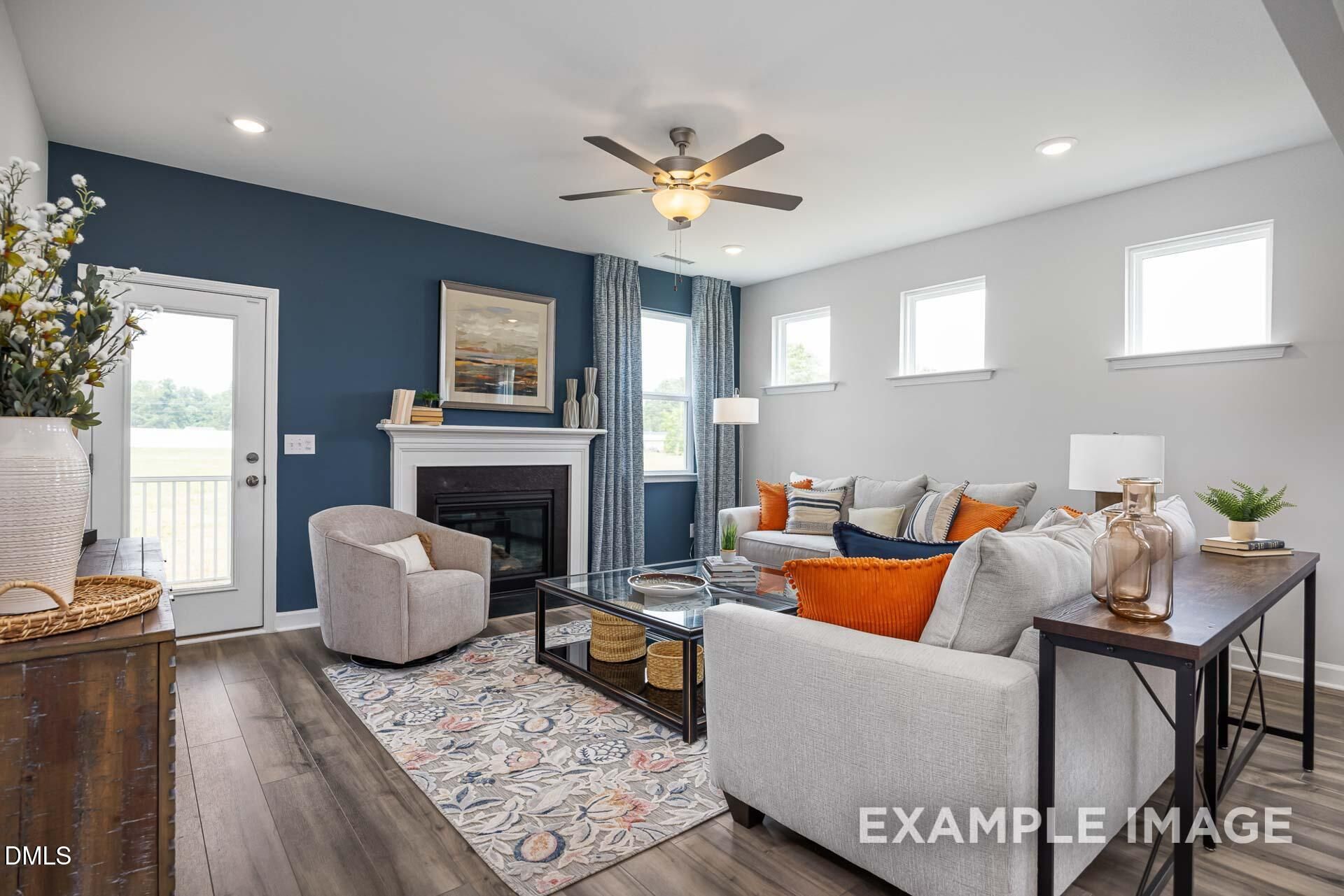Modern living room with fireplace and blue accent wall in The Adalynn A floor plan at Woodland Crossing, Zebulon, NC.