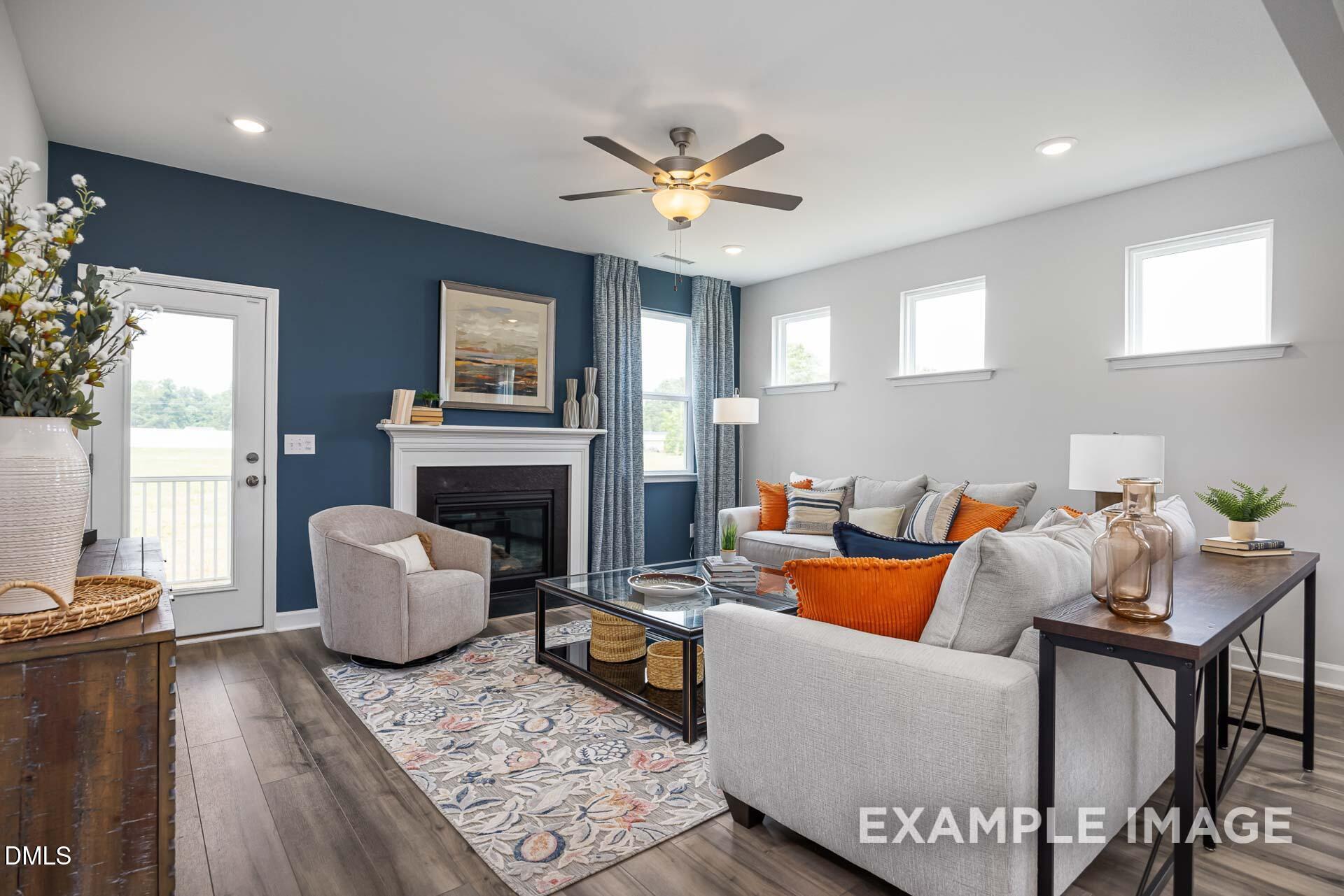 Modern living room with fireplace and blue accent wall in The Adalynn A floor plan at Woodland Crossing, Zebulon, NC.