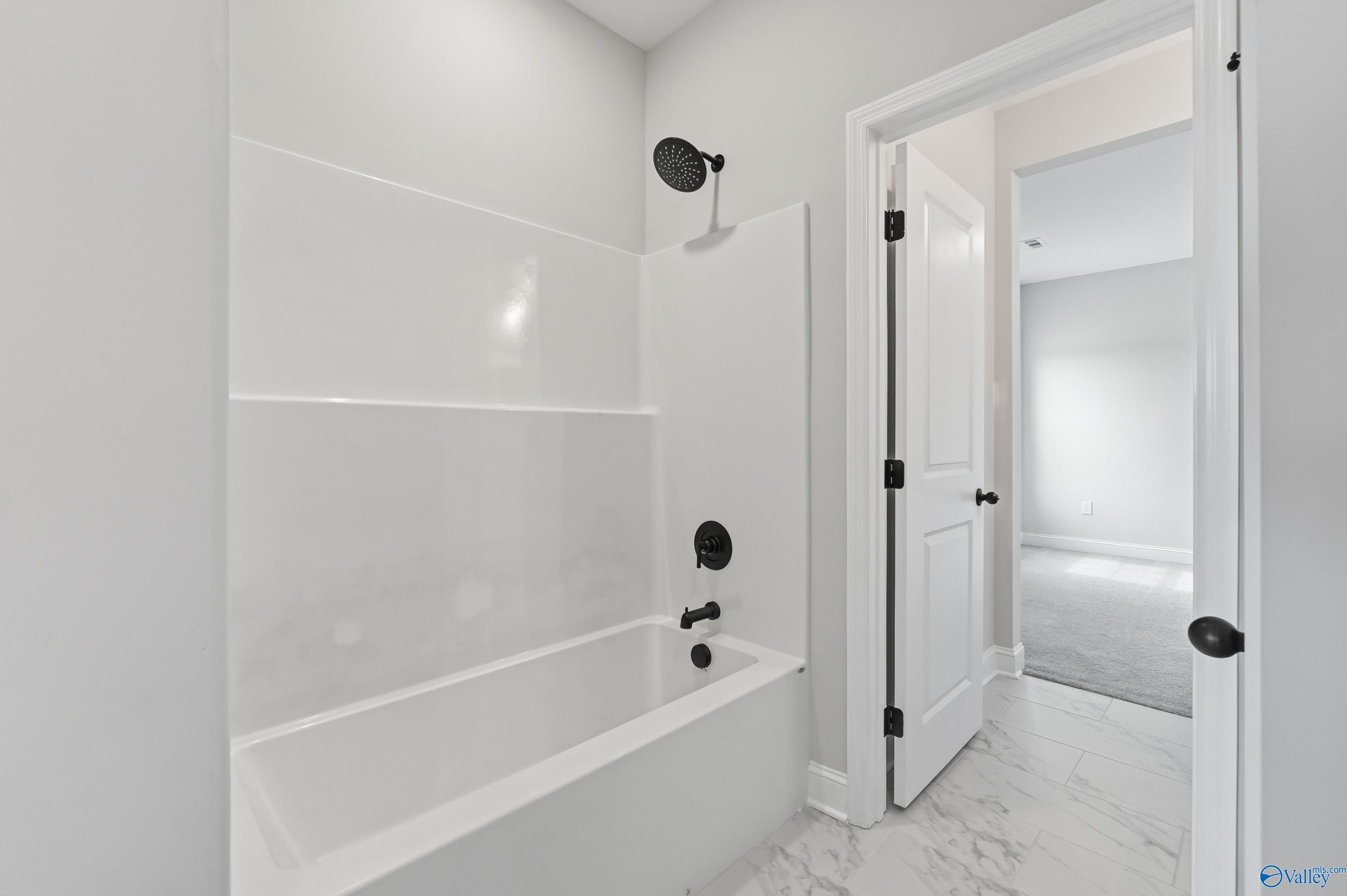 Elegant white subway tile shower and soaking tub with black fixtures in Davidson Homes The Finleigh, Meridianville, AL