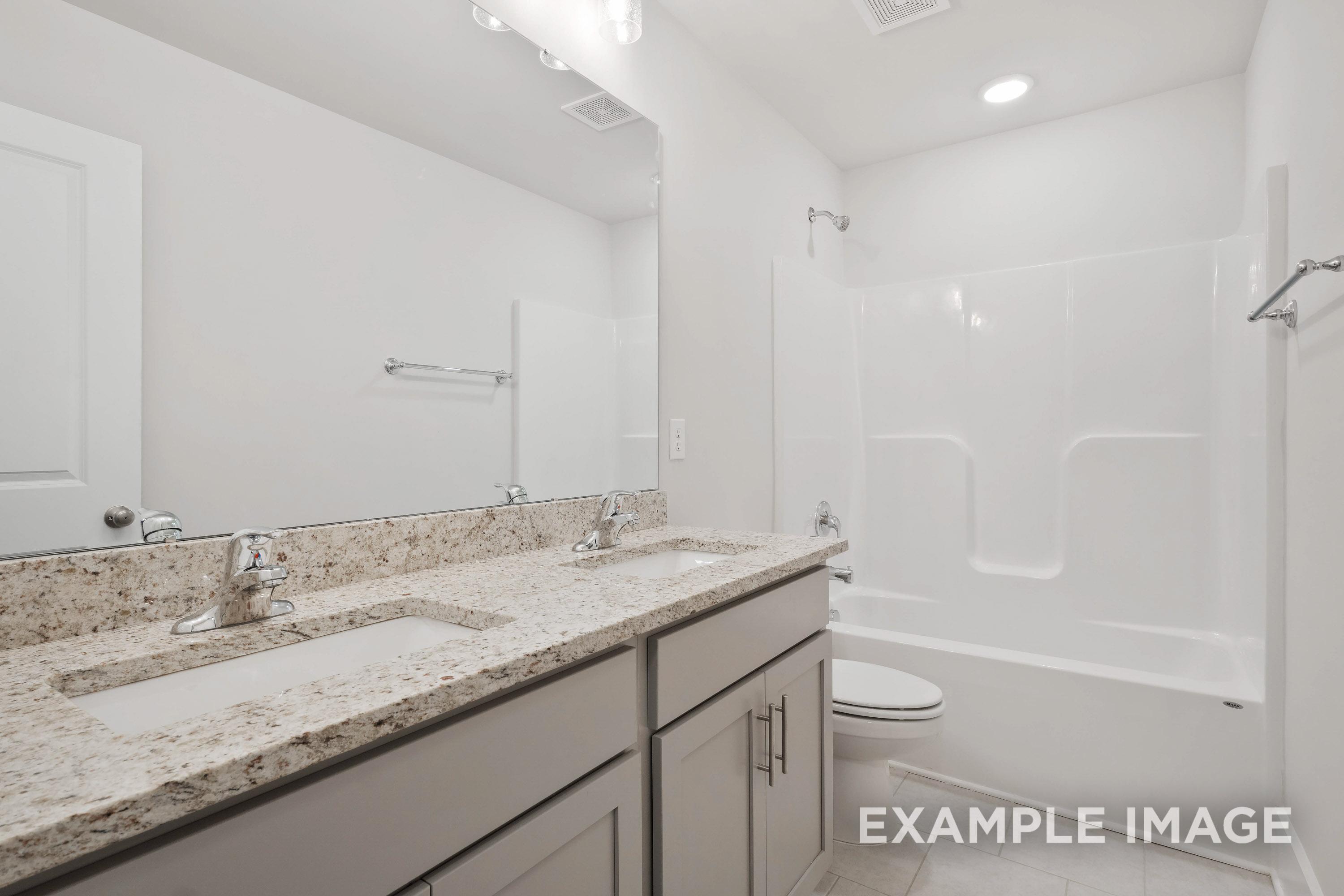Modern bathroom in The Richmond D featuring a dual-sink granite vanity, light grey cabinetry, and a full tub-shower combo.