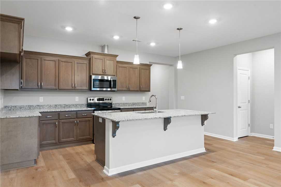 Modern kitchen with taupe shaker cabinets, white quartz island, stainless appliances in The Luna B by Davidson Homes, Opelika AL