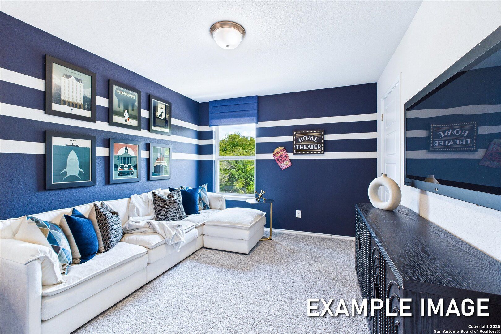 Navy blue media room with white striped walls, L-shaped sofa, mounted TV, art prints in Davidson Homes The Gillian B, San Antonio