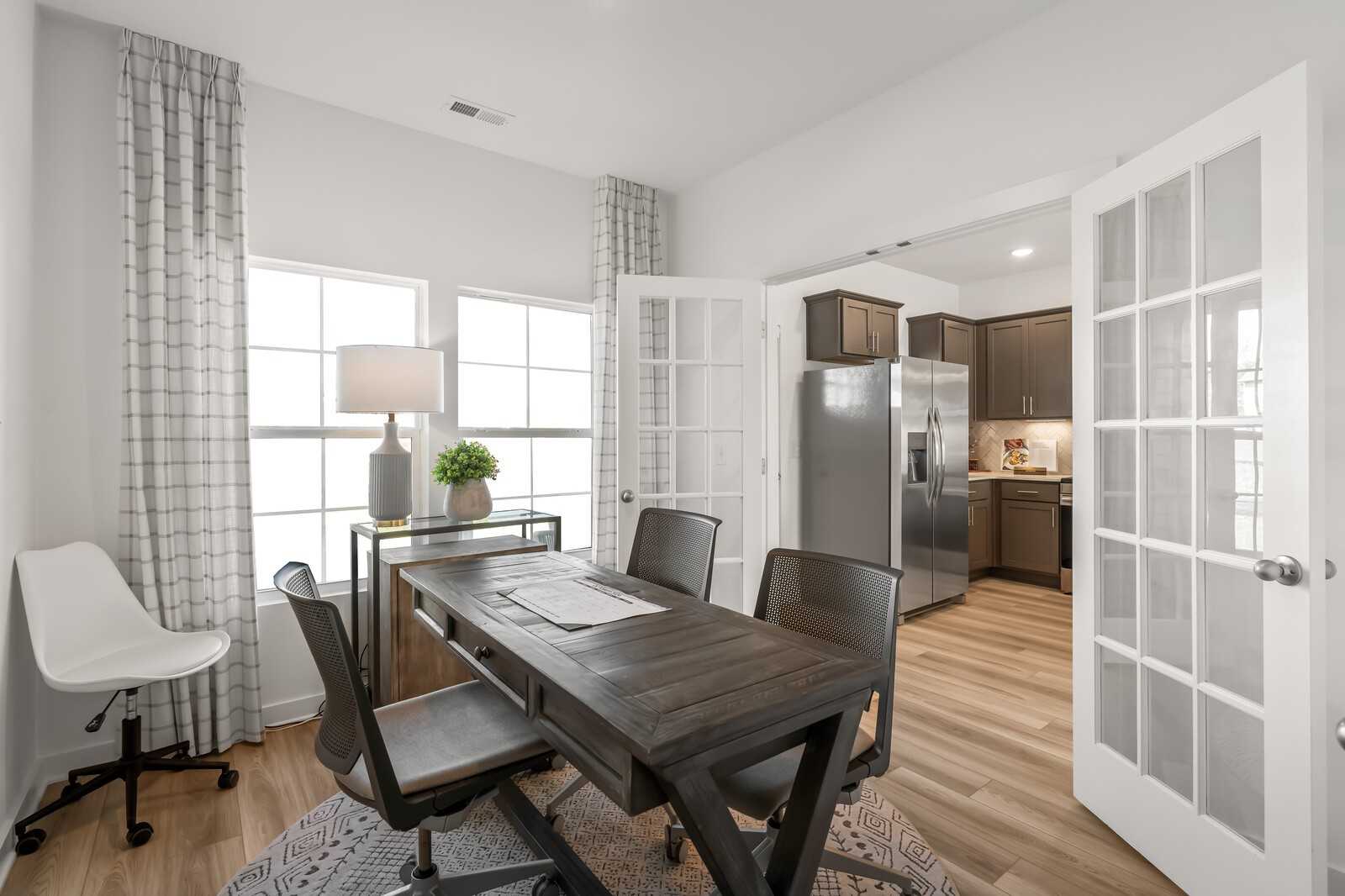 Cozy home office with wooden desk, swivel chair, and French doors to stainless kitchen in Davidson Homes Cumberland B, Gallatin TN