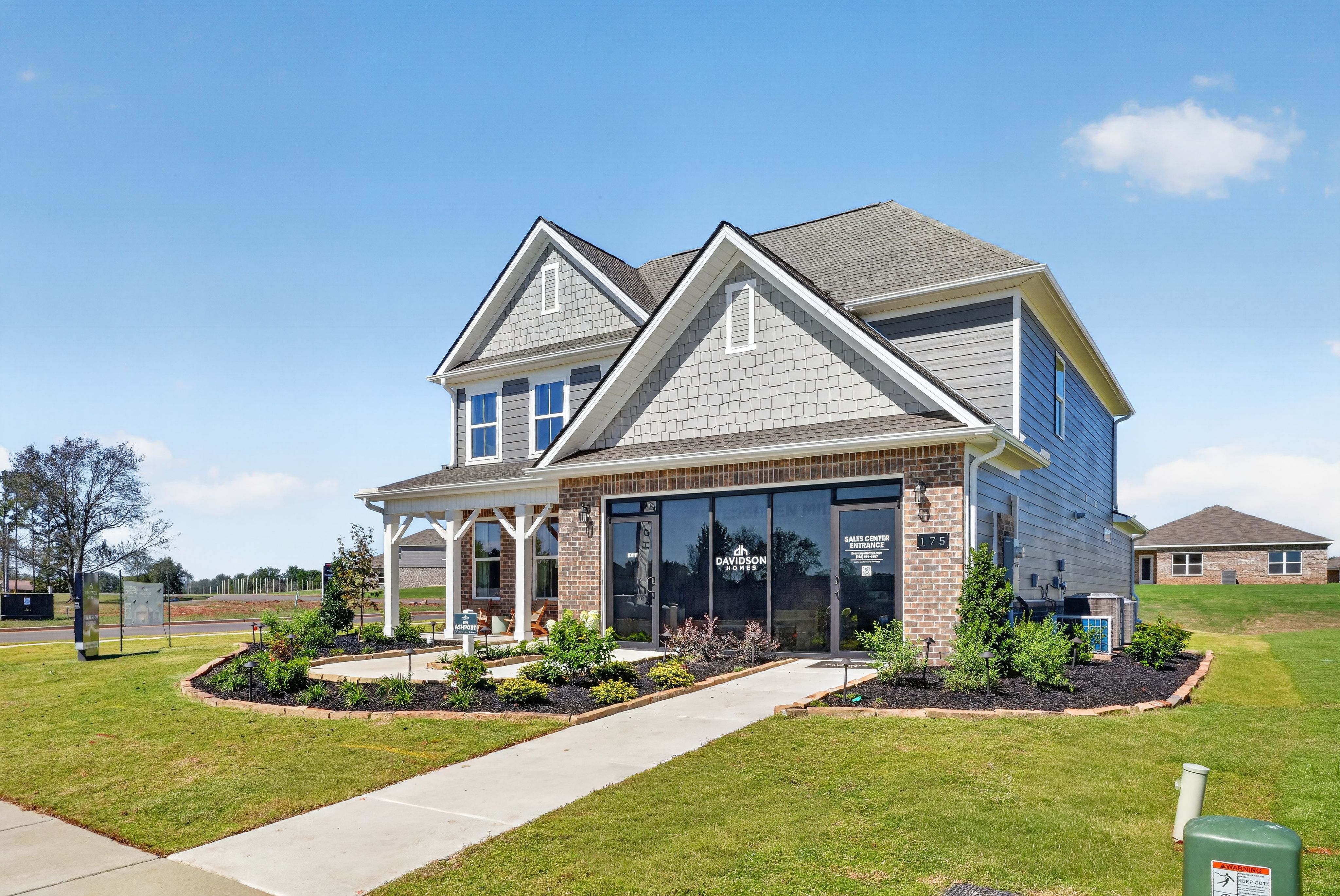 Davidson Homes sales center exterior at Evergreen Mill in Madison, Alabama with brick facade, covered porch, and landscaped yard